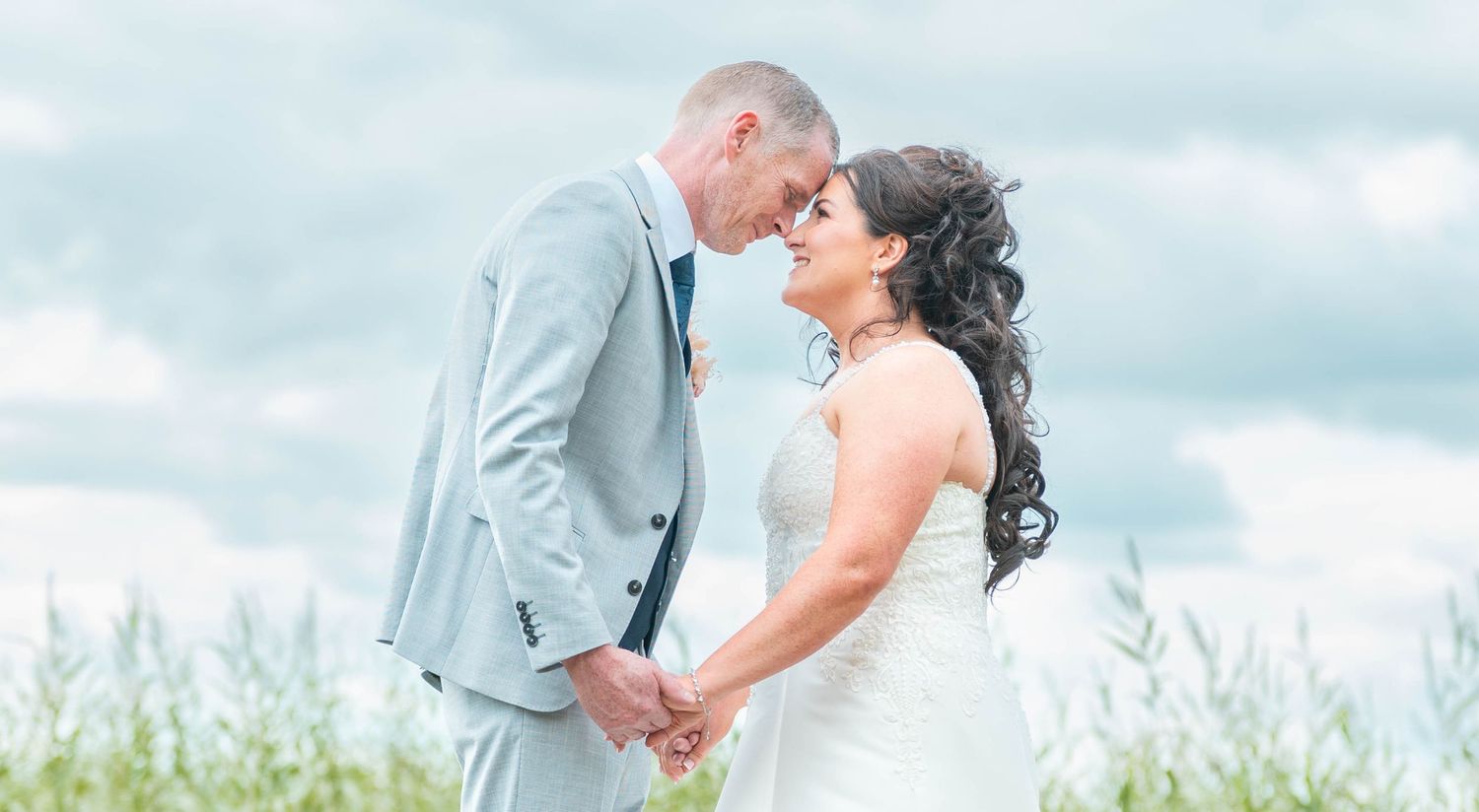 Bride and groom holding hands and sharing a romantic moment outdoors on their wedding day.