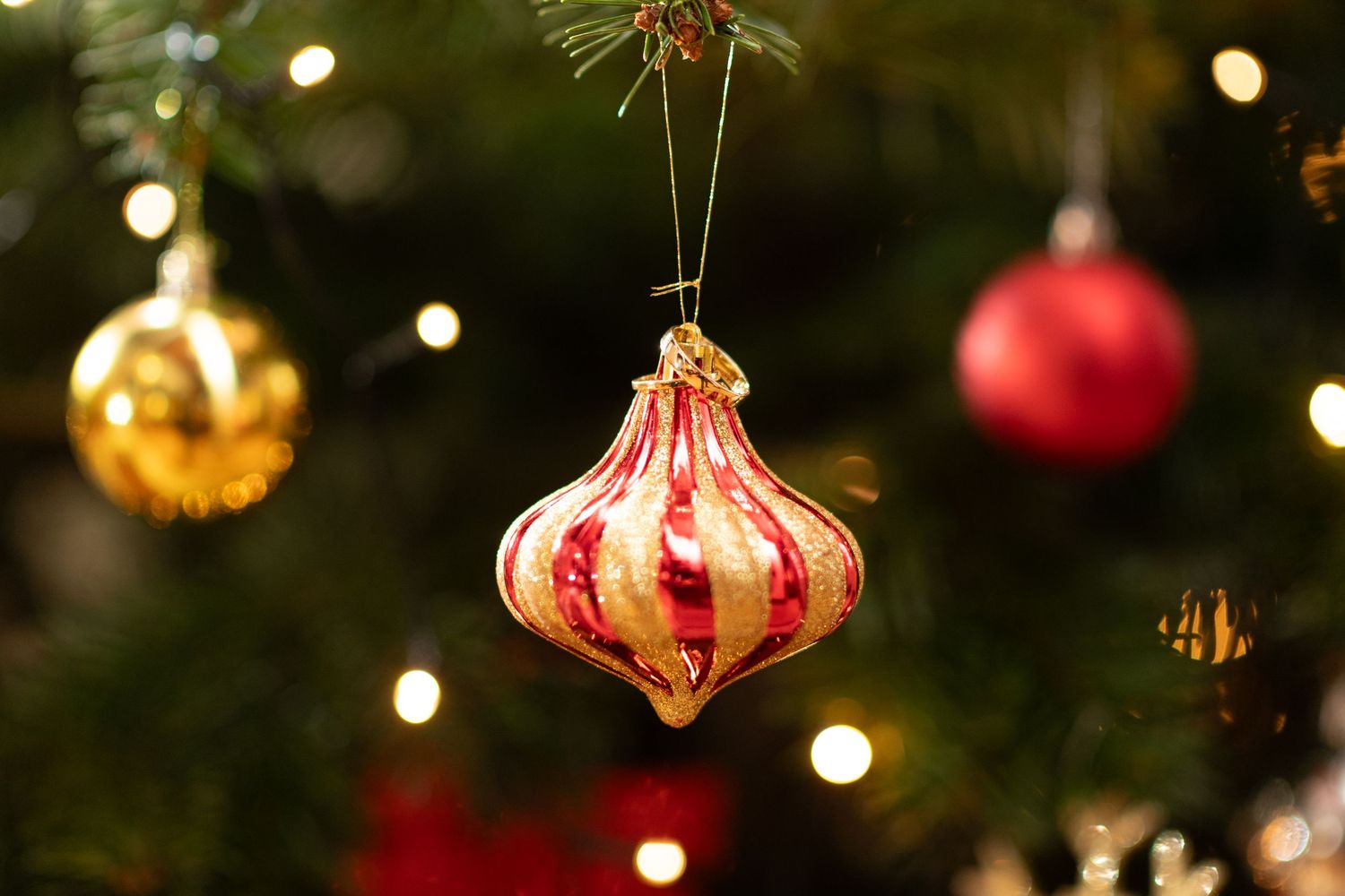 Vintage-style Christmas ornaments hanging on tree with bokeh lights.