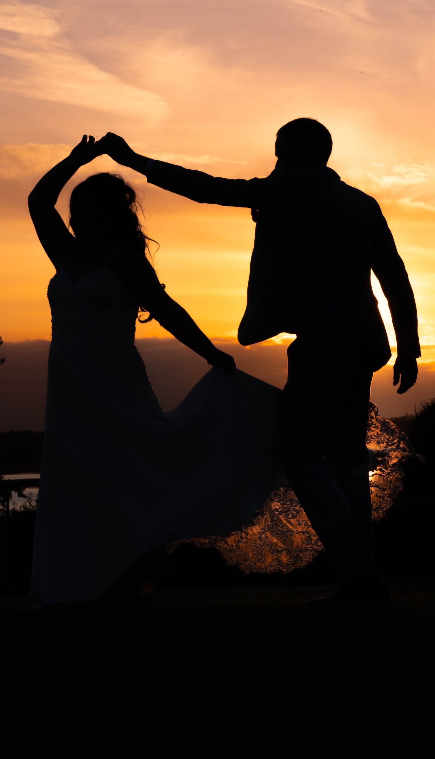Silhouettes of a couple dancing against a dramatic sunset sky.