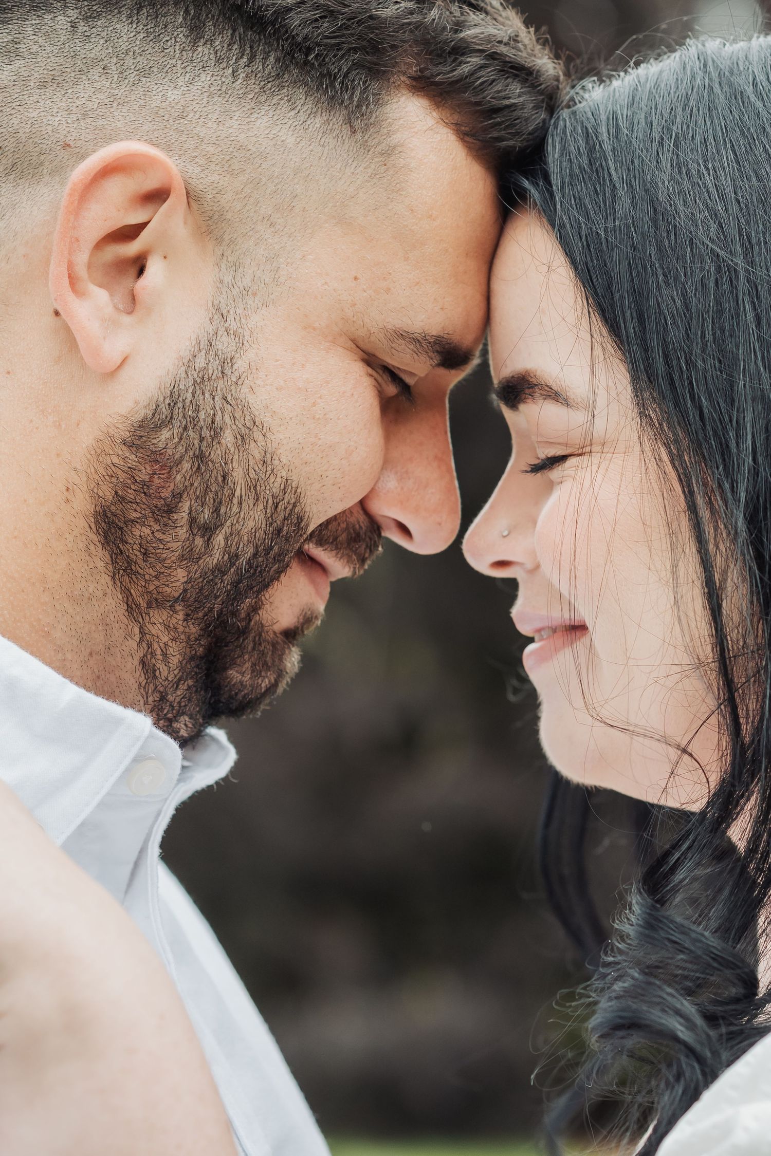 Intimate close-up portrait of couple sharing tender moment outdoors.