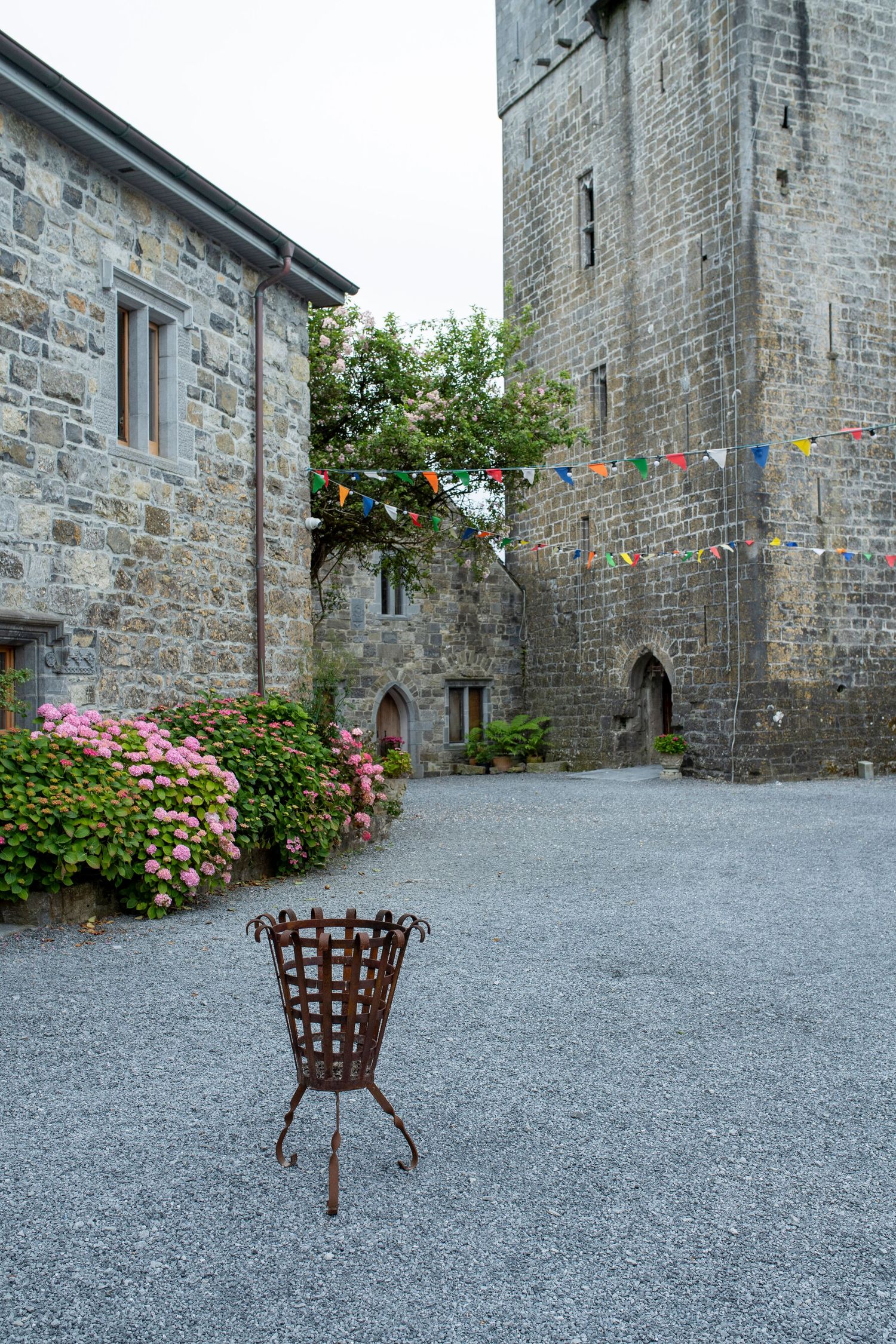 Historic stone building courtyard with gravel ground and decorative flower planters.