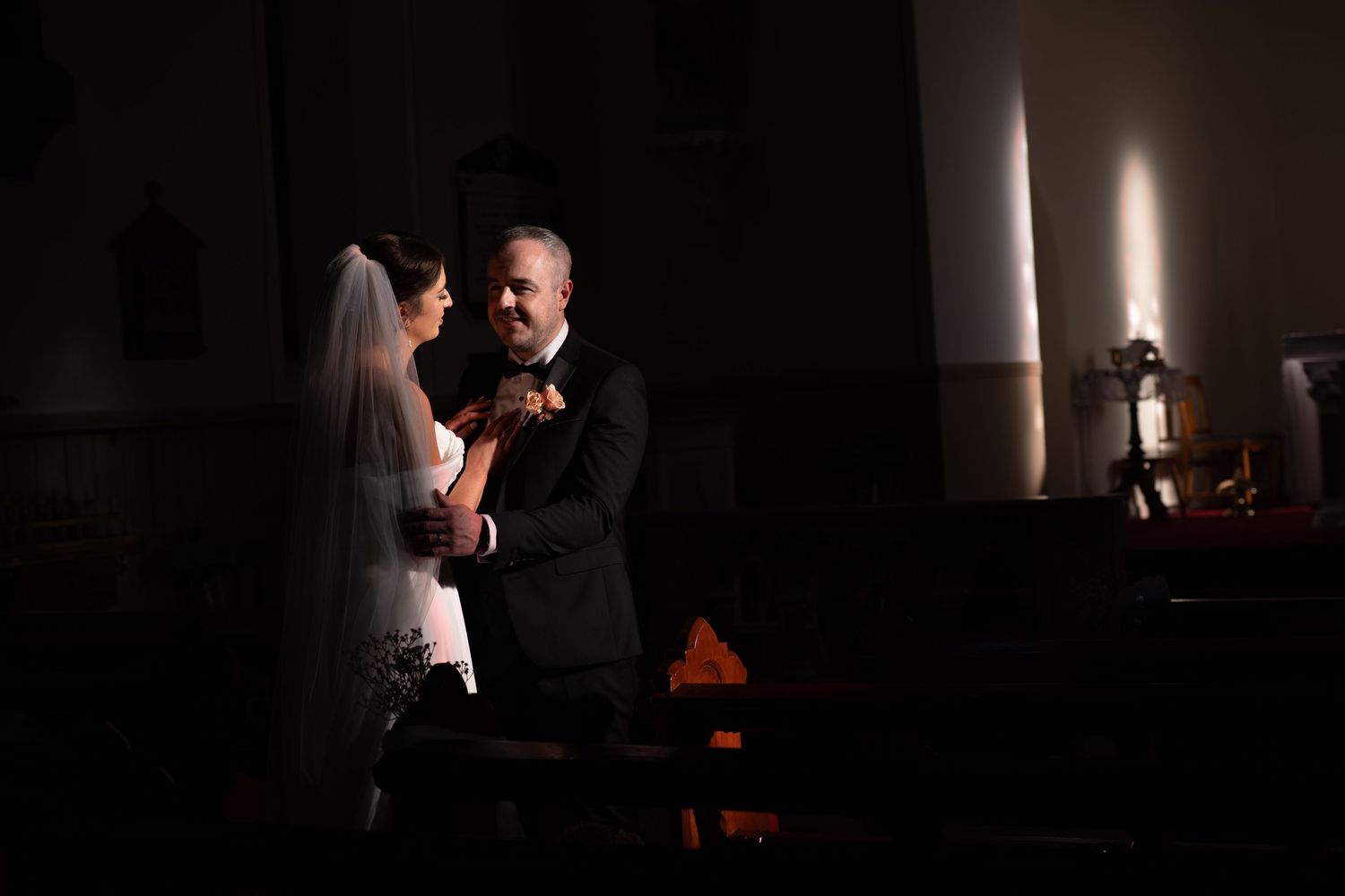 Intimate wedding moments captured in low light with dramatic shadows.