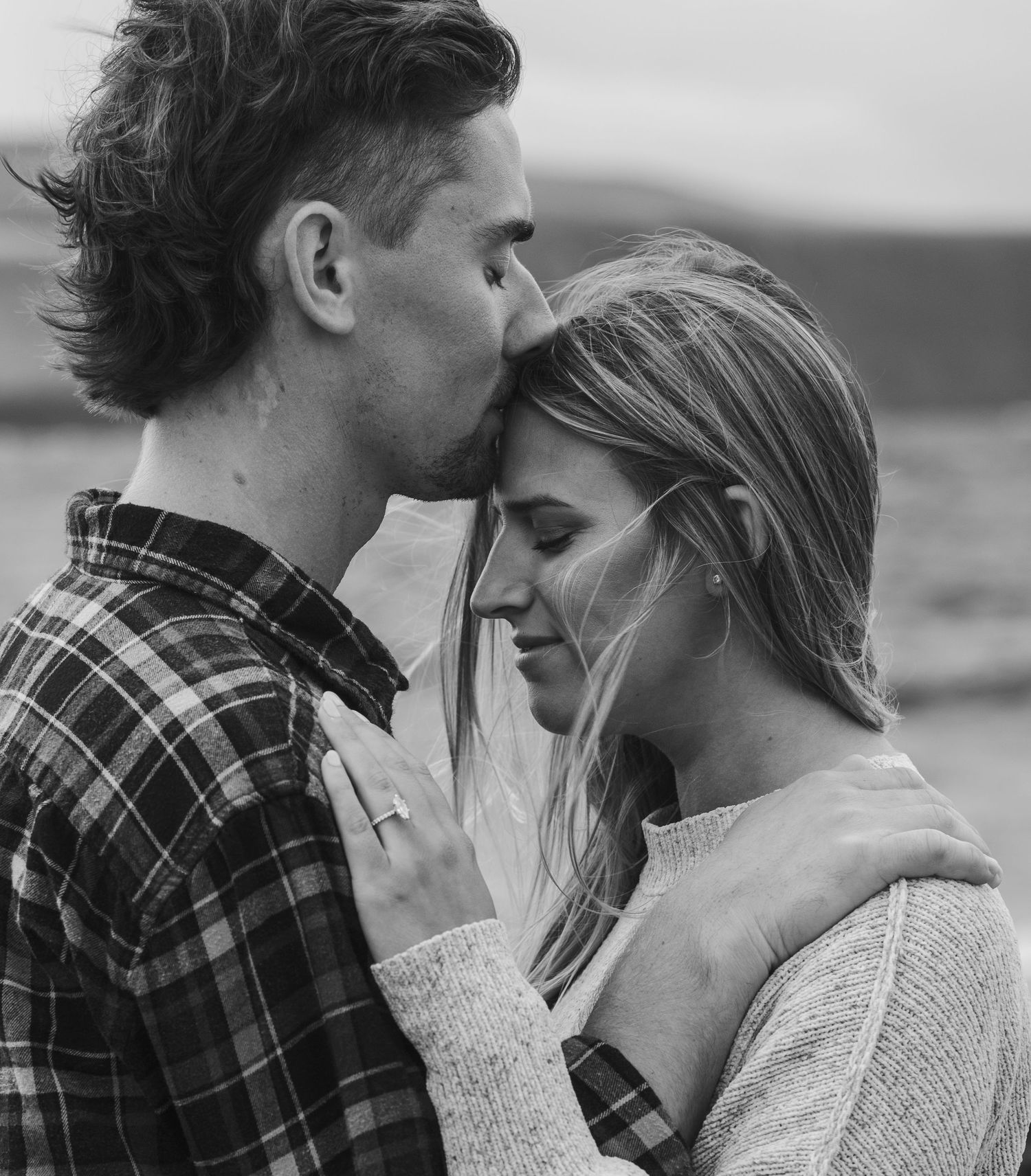 Black and white intimate portrait of couple in romantic embrace by the sea.