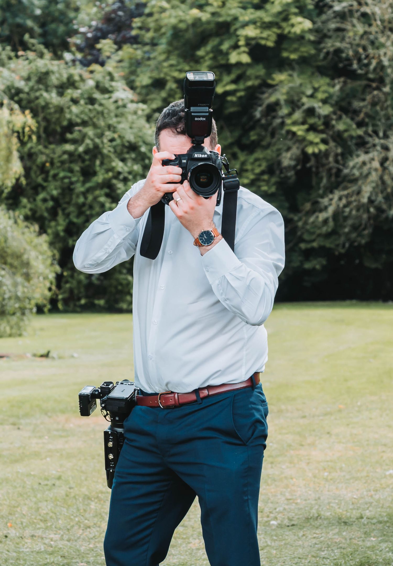 Professional photographer in blue pants taking pictures in a garden setting.