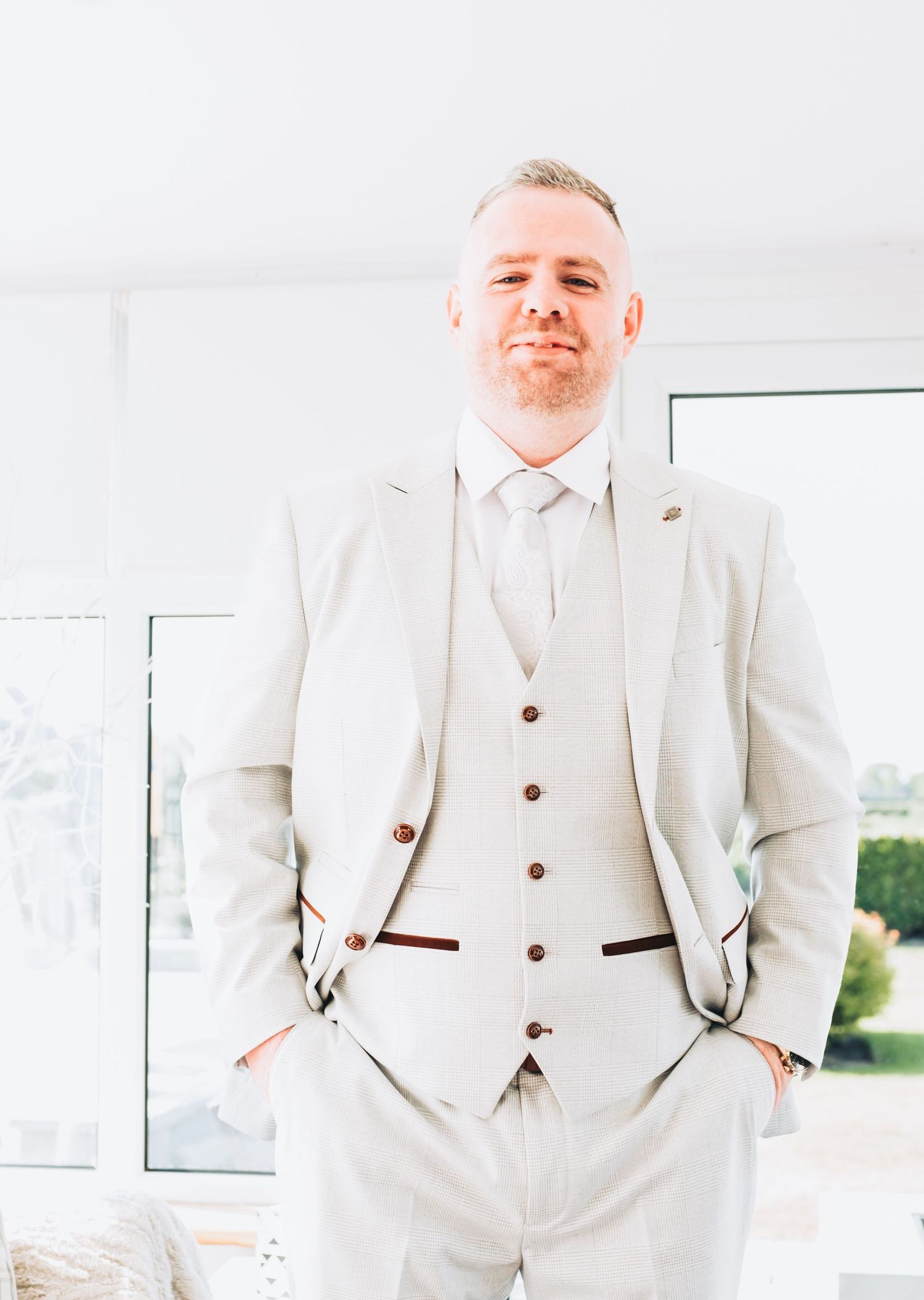 Person wearing a crisp white three-piece suit poses confidently in a bright setting.