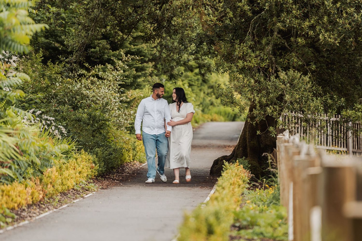 Couple walking along a scenic garden path surrounded by lush greenery.