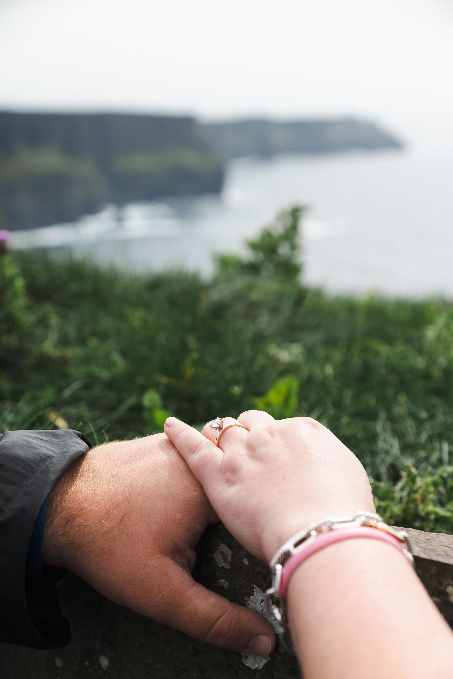 Couple lying in grass overlooking scenic coastal cliffs and ocean views in Ireland.