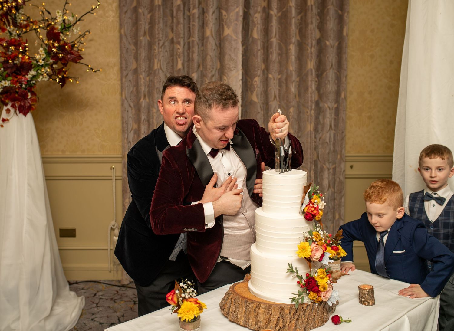 Wedding cake display with rustic wood elements and autumn-colored floral decorations.