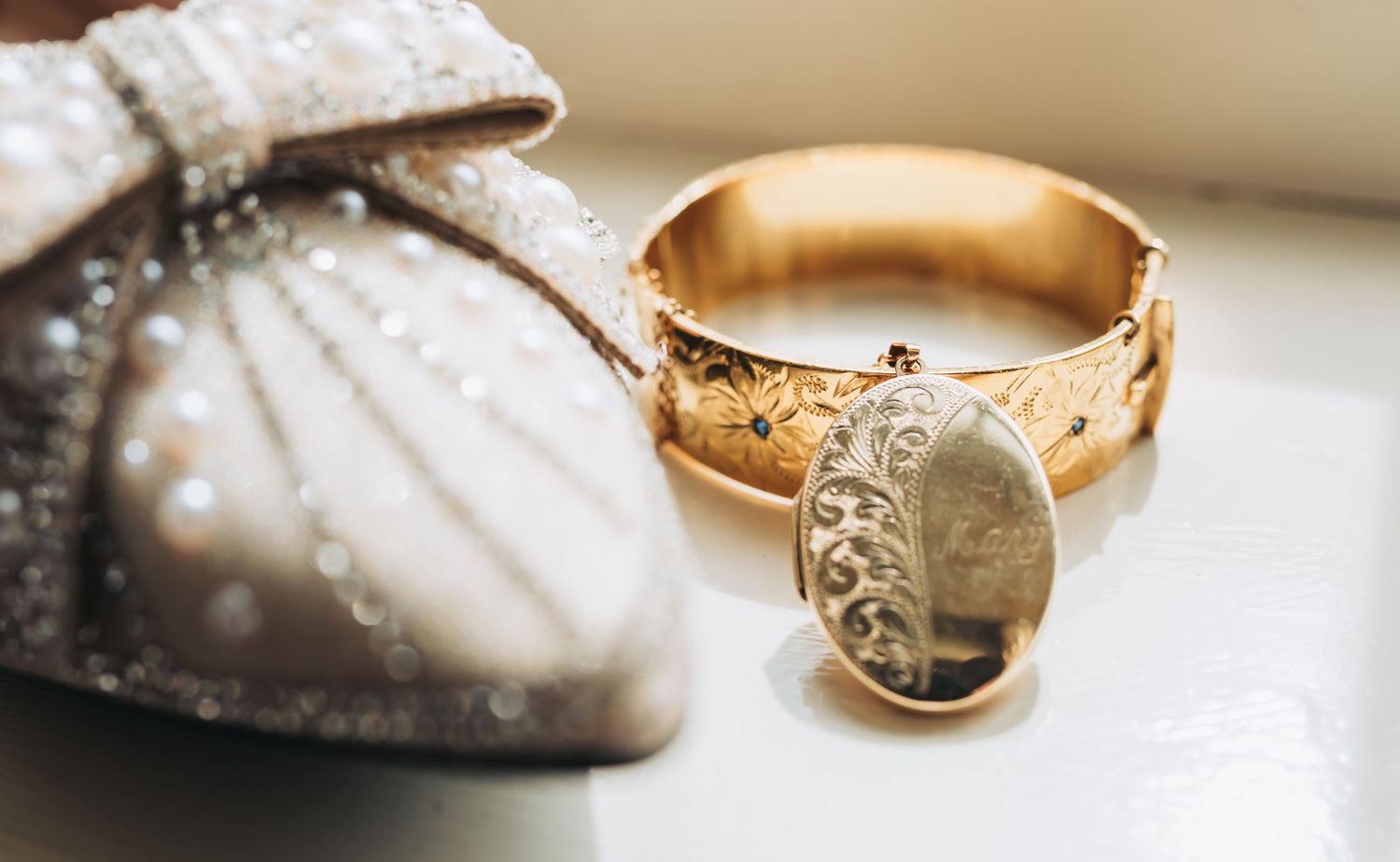 Wedding rings and jewelry details photographed on a light surface with shallow depth of field.