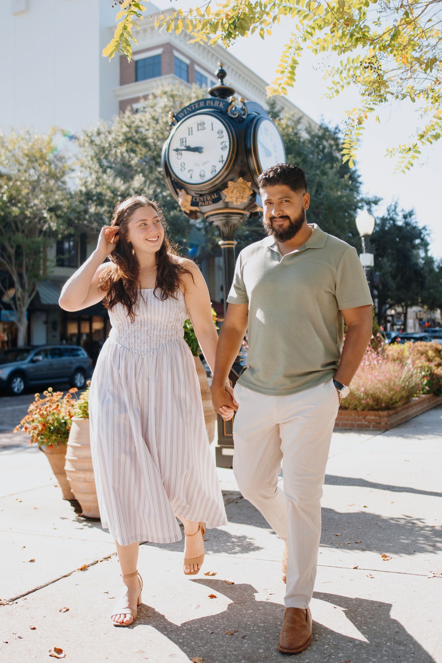 A couple in white outfits share joyful moments together while walking outdoors on a sunny autumn day.