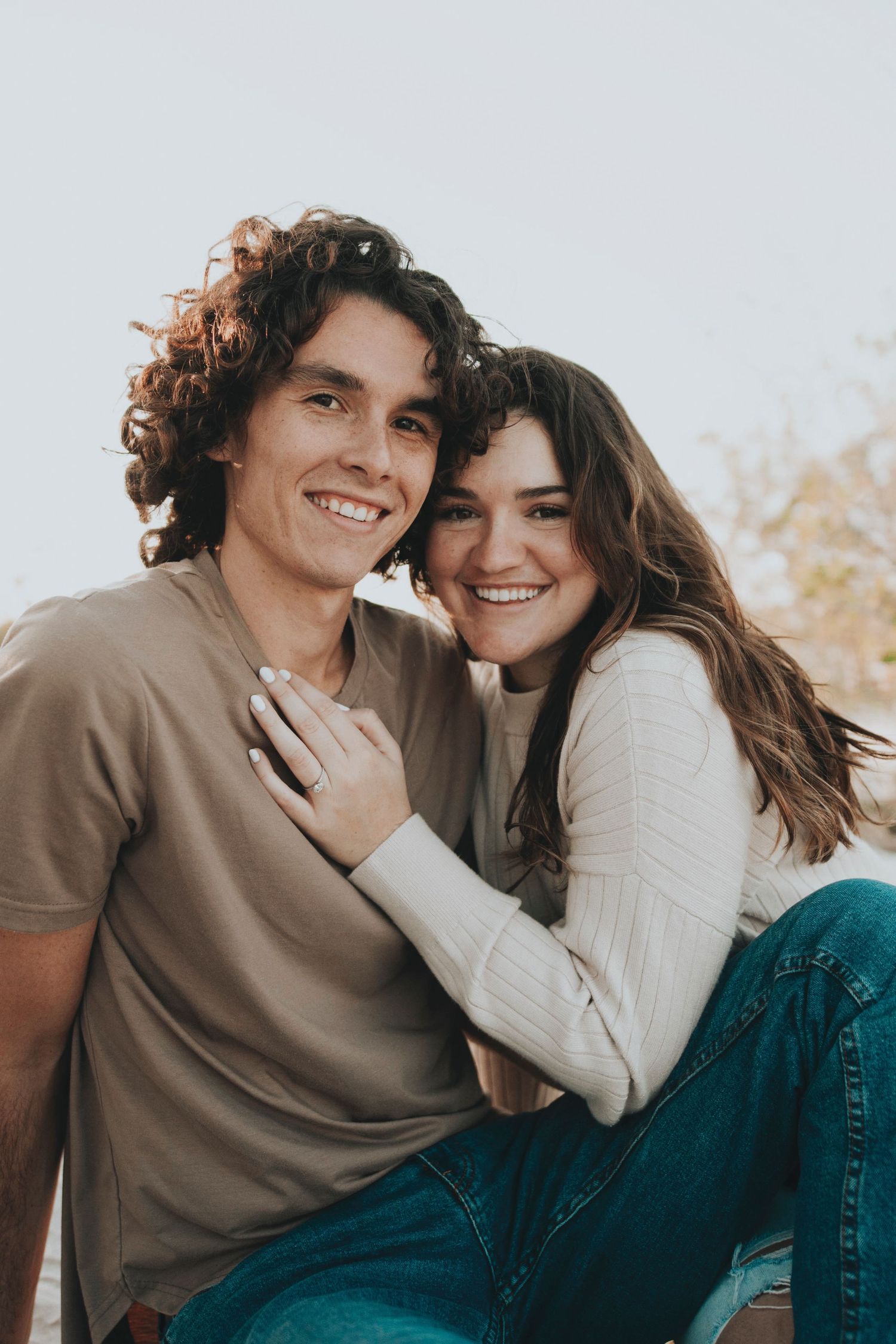 Candid outdoor portrait of couple laughing and embracing in casual attire.