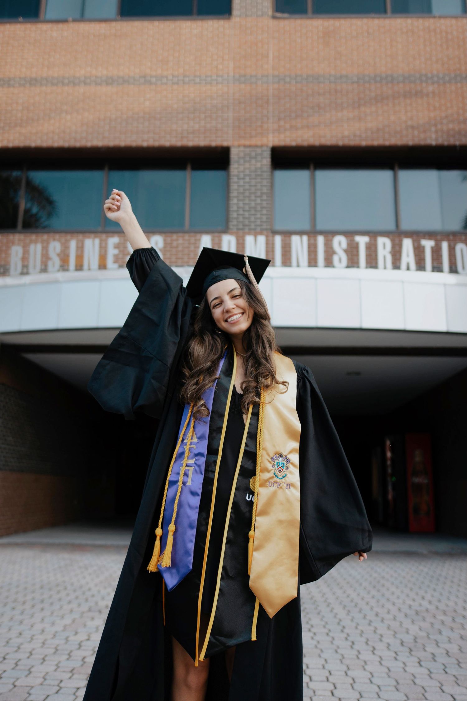 Graduation celebration photos showing two graduates in black robes and honor cords jumping with joy.
