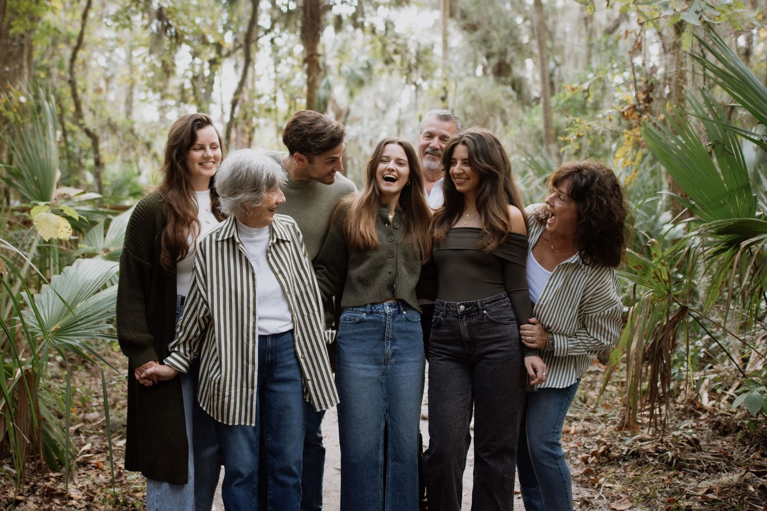 A group of people standing together and laughing in a lush outdoor garden setting.