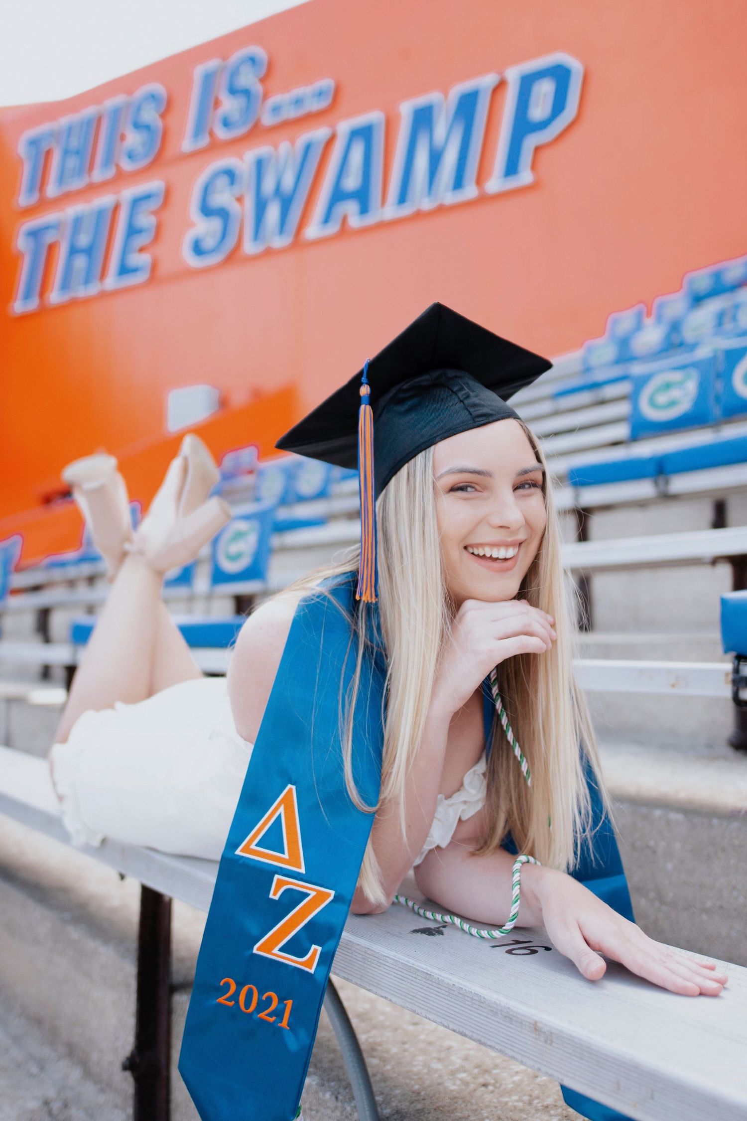Graduate in blue Delta Zeta stole poses at The Swamp stadium during graduation photoshoot.