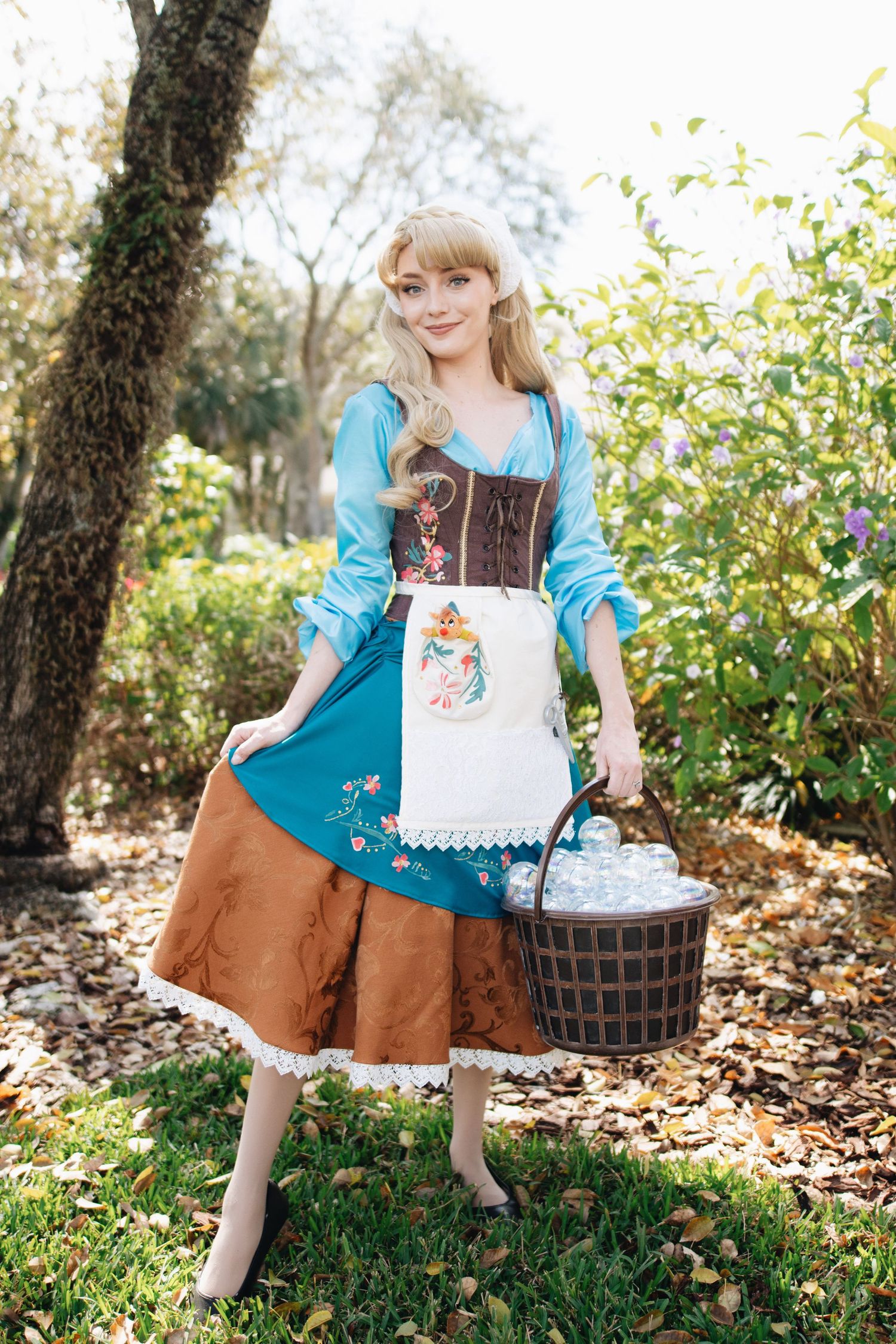 A character in traditional peasant attire poses with a basket in a garden setting.