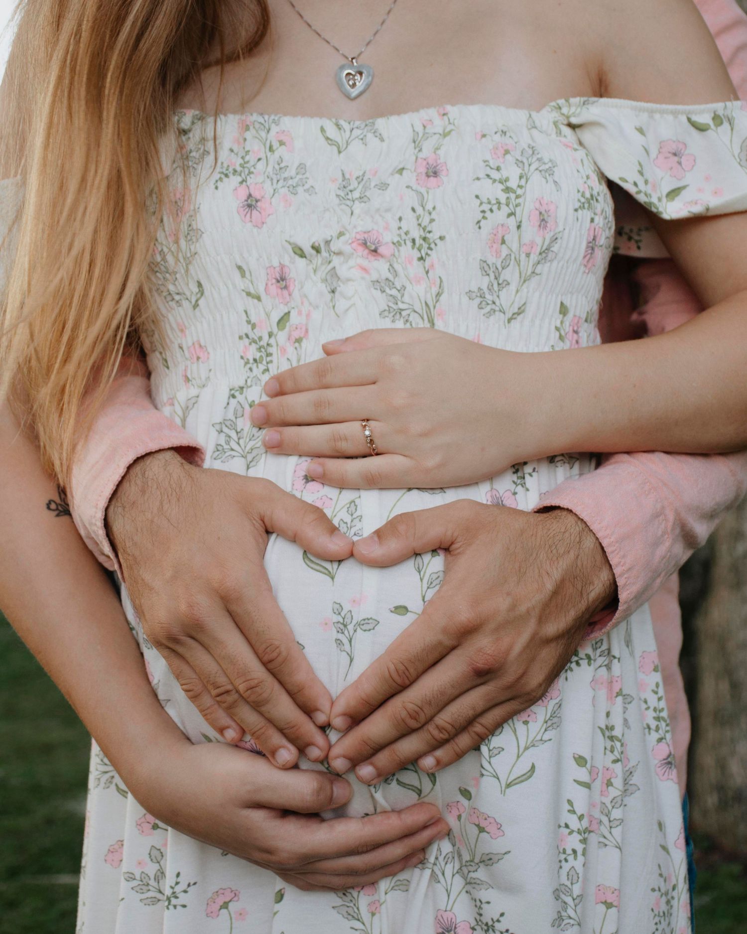 Close-up shots of loving hands cradling a baby bump in a floral maternity dress.