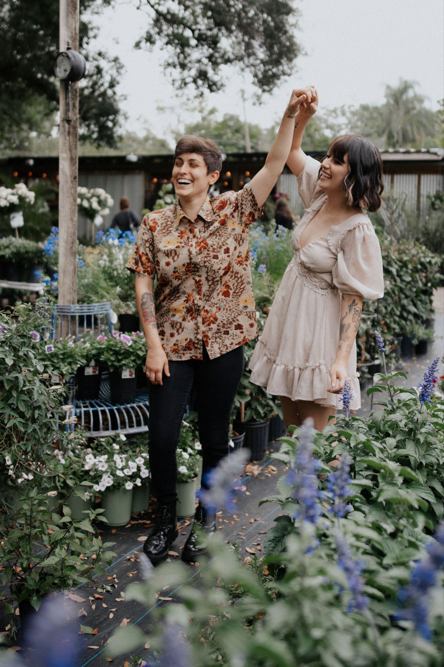 A couple dancing and laughing in a garden with blooming blue flowers.