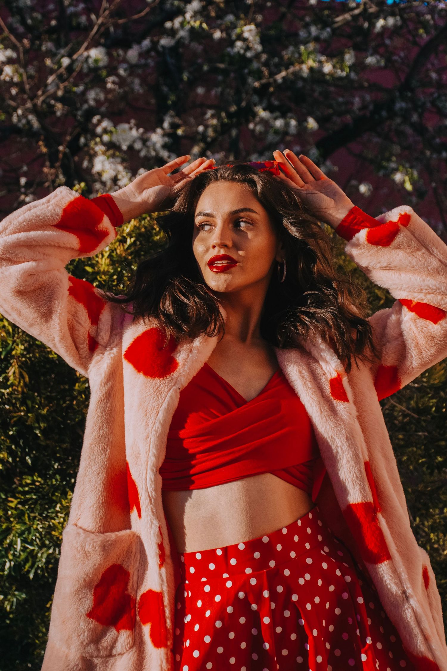 Artistic fashion photos with red and white polka dot clothing against flowering bushes.