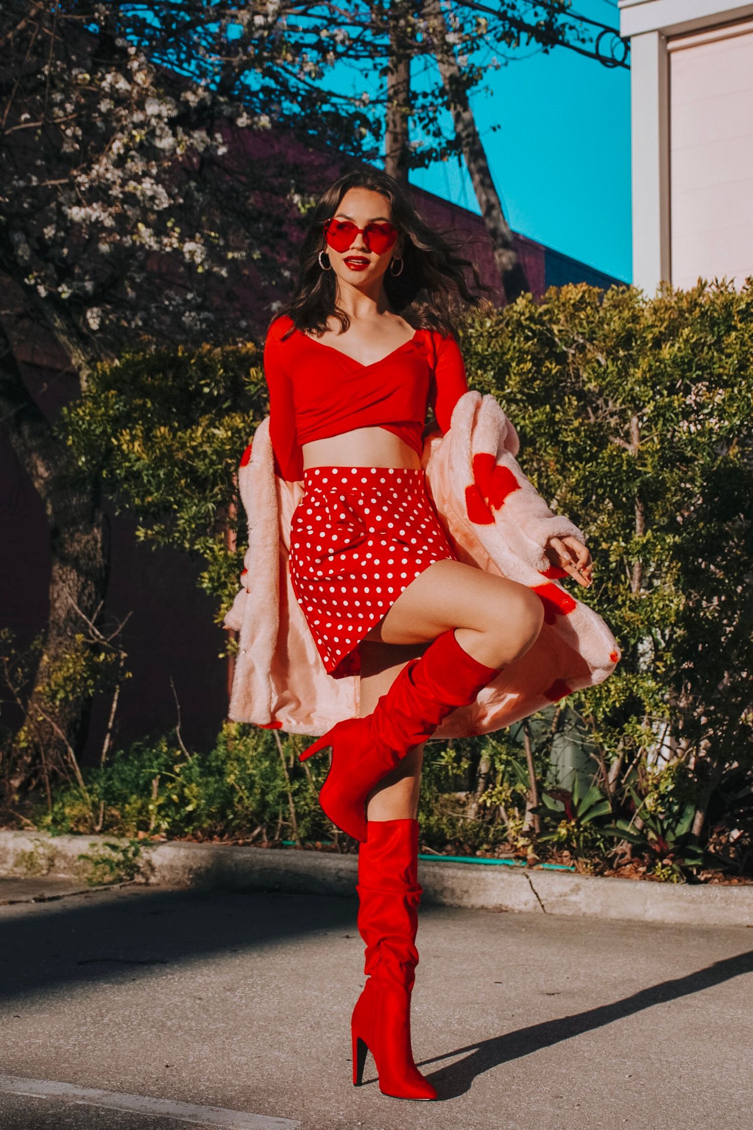 Retro inspired photoshoot featuring red polka dot outfit with matching boots in outdoor setting.