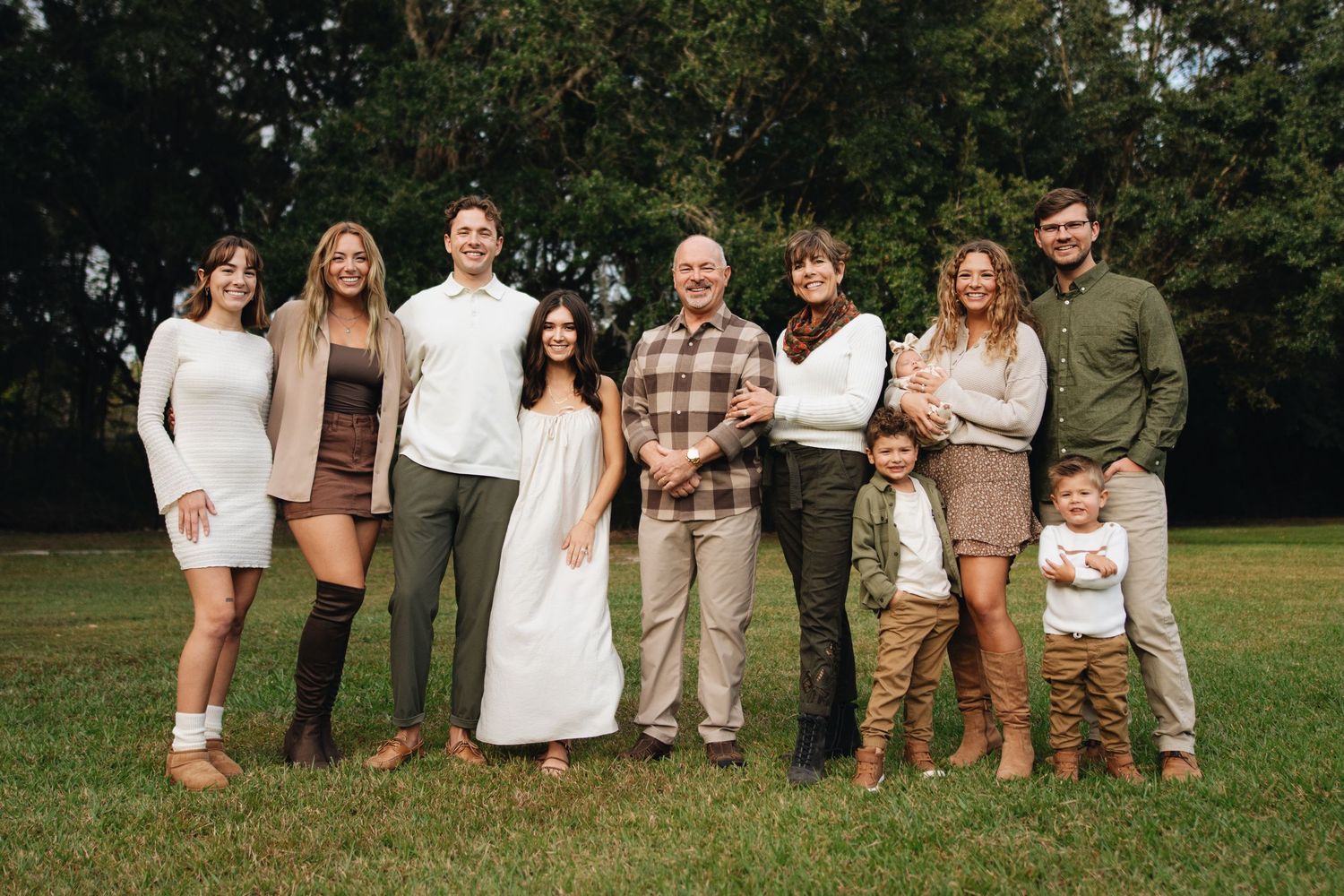 A group poses outdoors in coordinated neutral-toned outfits for a casual photo session in a grassy field.