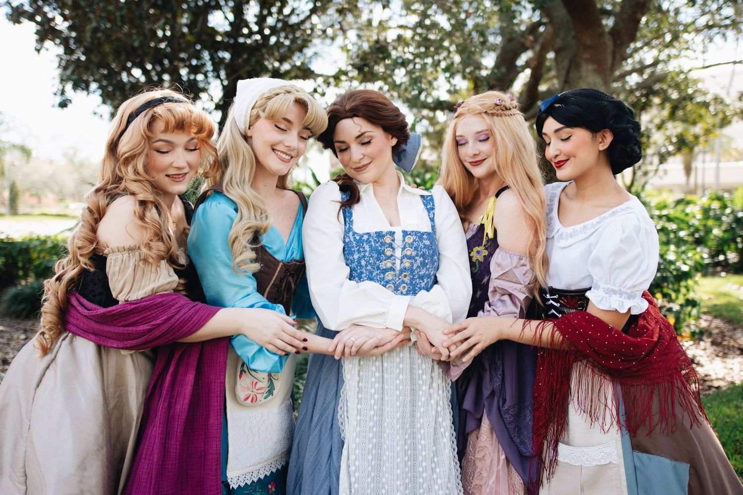 Group photo of women in vintage-inspired dresses posing together outdoors.