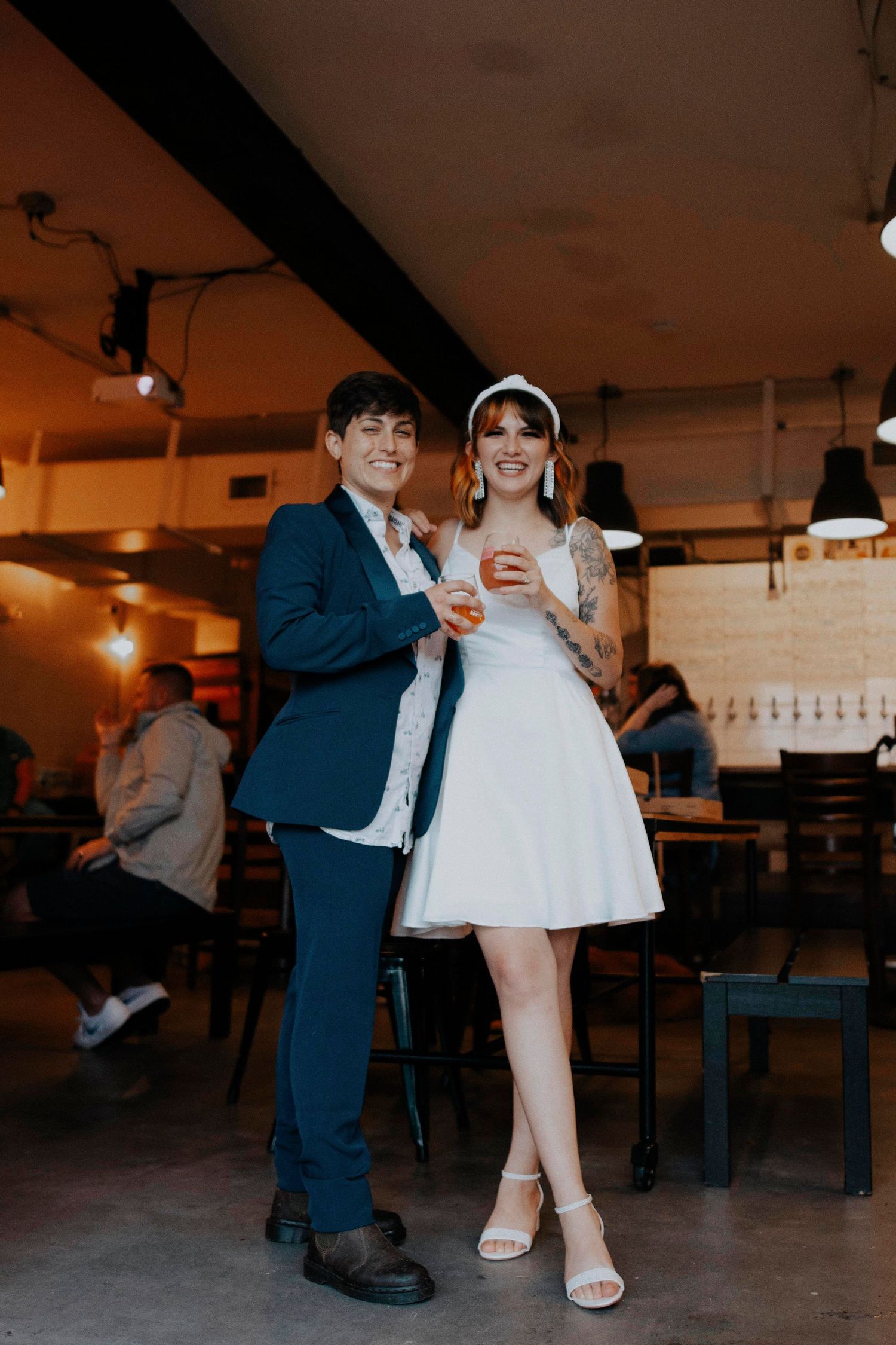 Couple in formal attire sharing playful moments in an industrial-style venue.