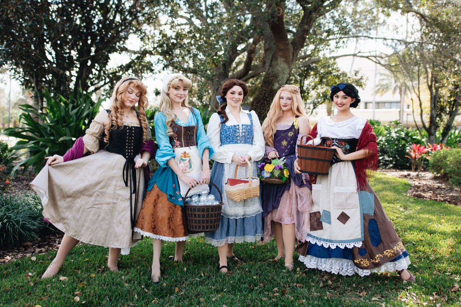 Outdoor group portrait featuring coordinated period costumes in a garden setting.