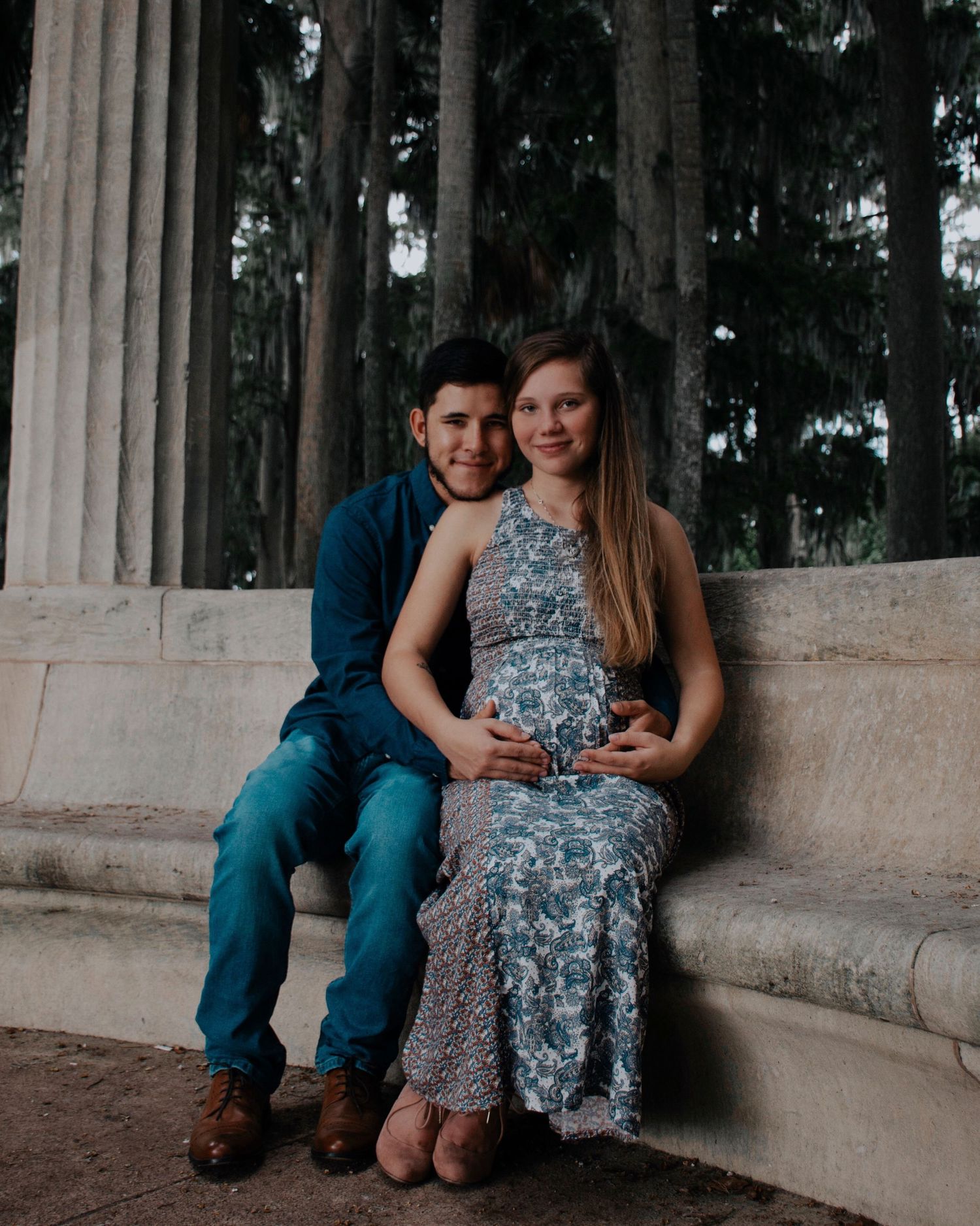 A tender moment captured between a couple sitting on stone steps outdoors.