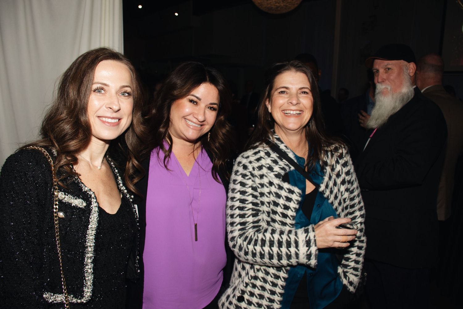 A group of people pose together at a nighttime social gathering or event.