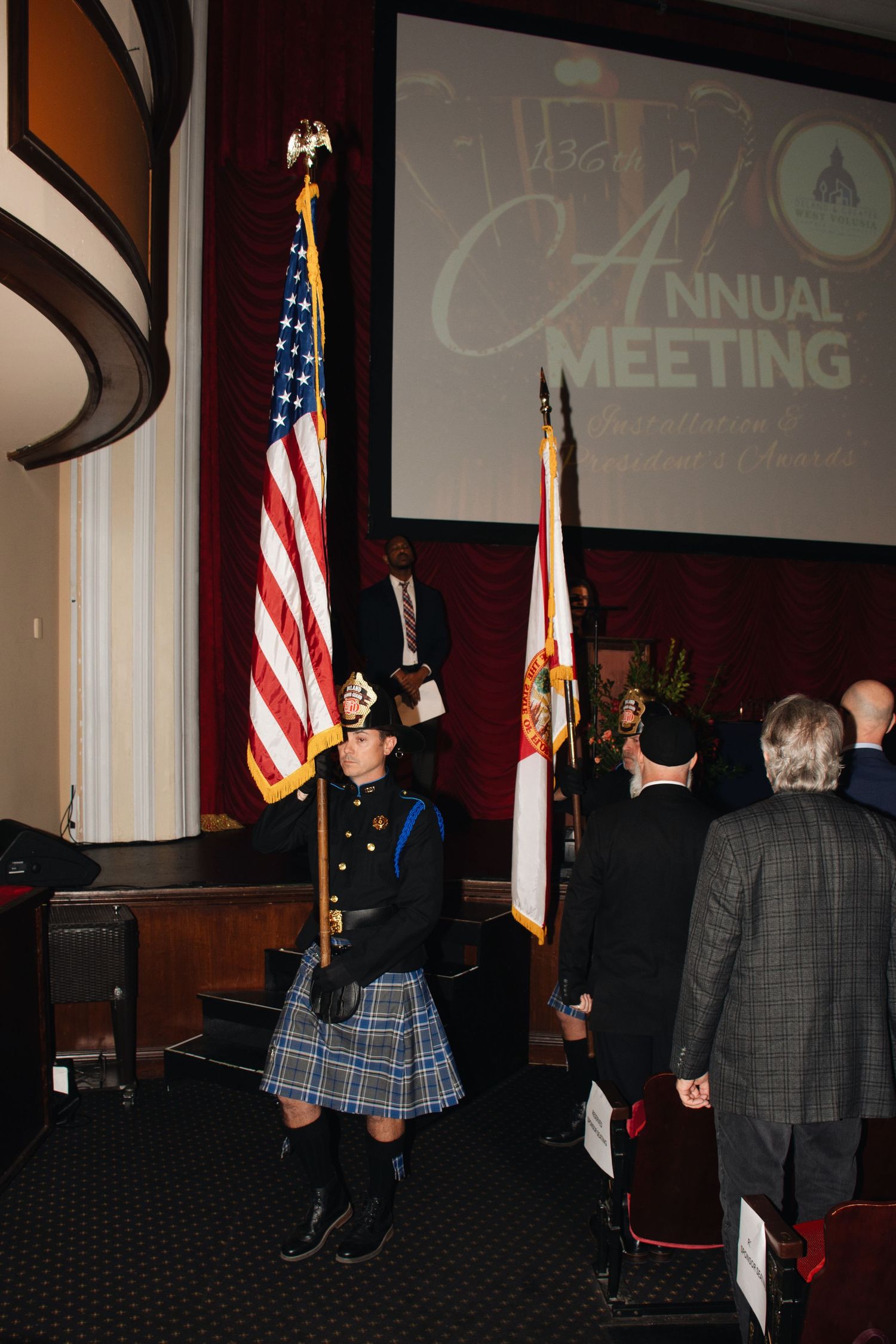 A sequence of five photos showing a formal ceremony with American flags and people standing in a dark conference room.