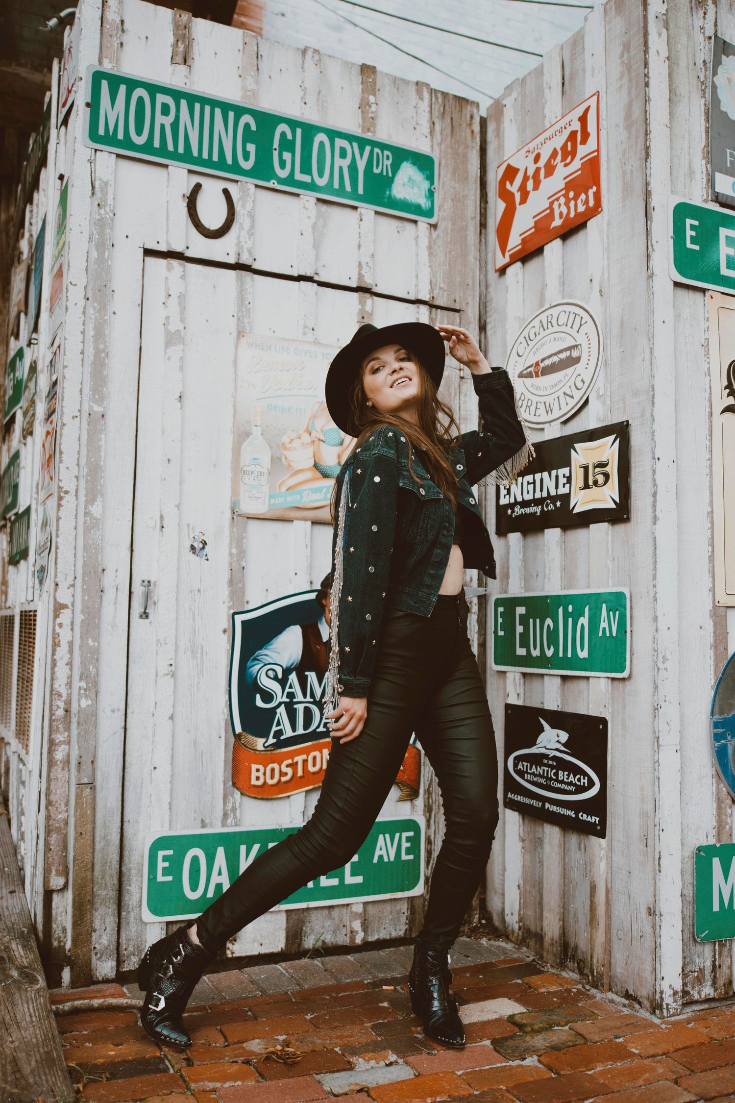 Dynamic fashion poses against wall decorated with street signs and vintage elements.