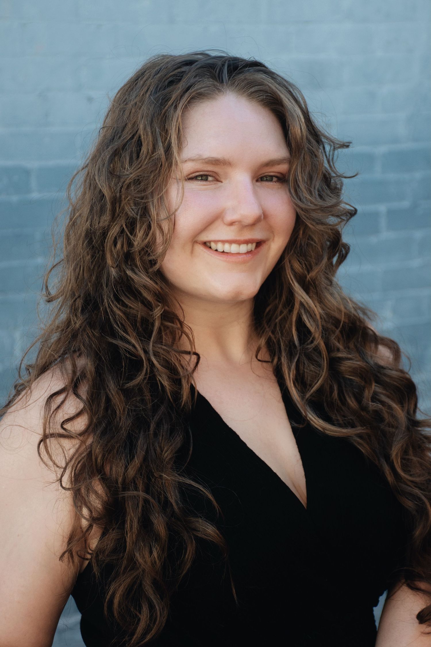 A portrait series showing joyful expressions against a blue brick wall background.