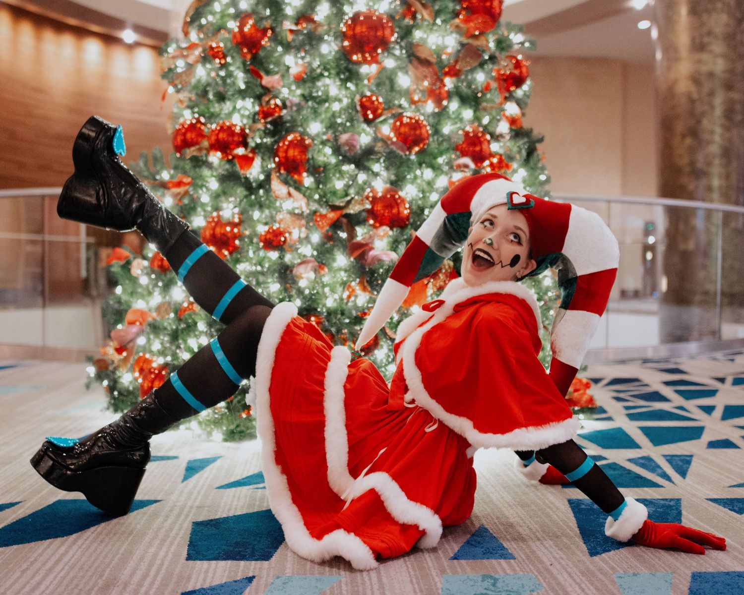 A festive holiday photoshoot sequence with a person in a red Santa outfit lying on the floor near a decorated Christmas tree.
