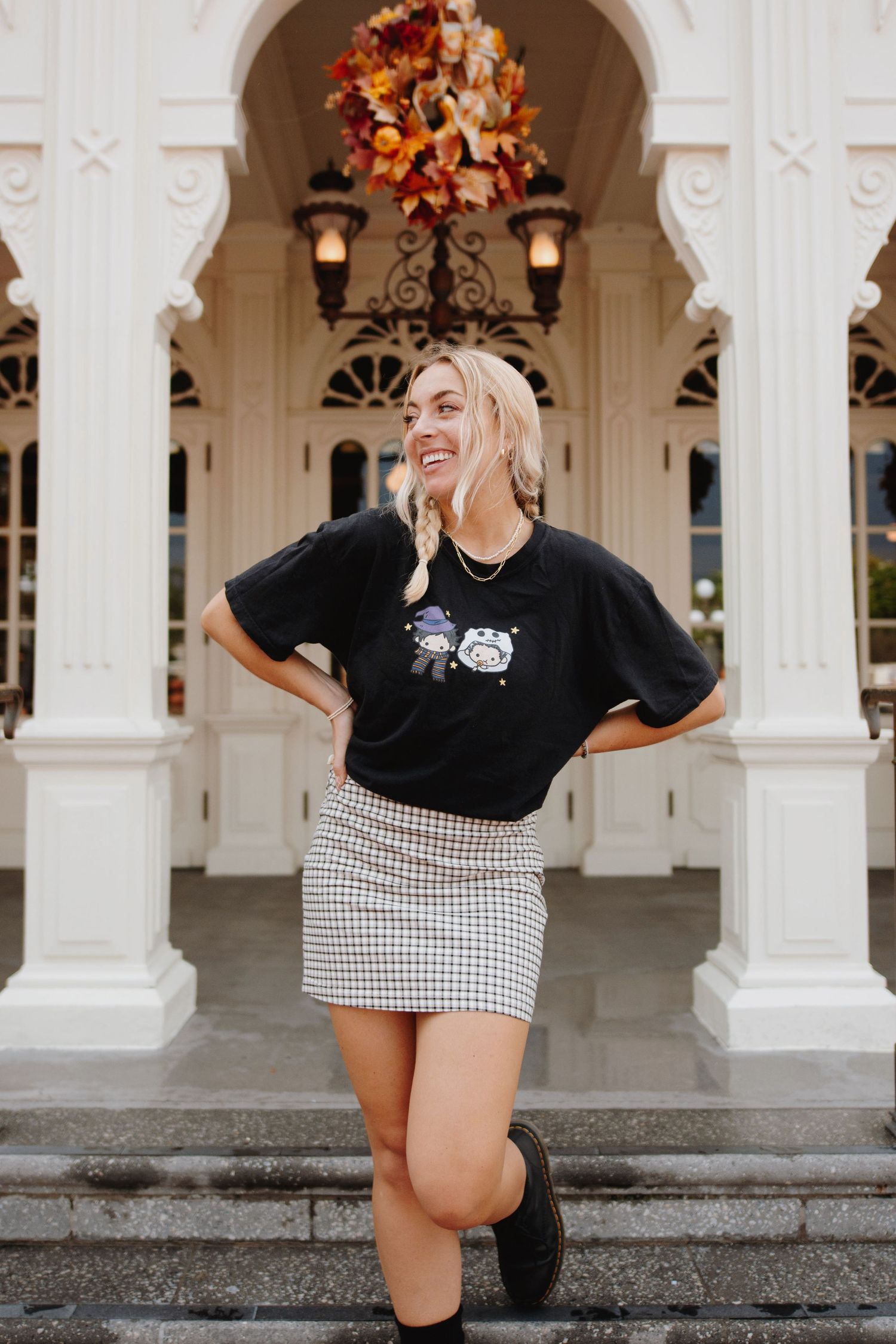 Playful fashion photoshoot in front of white colonial architecture with autumn decorations.