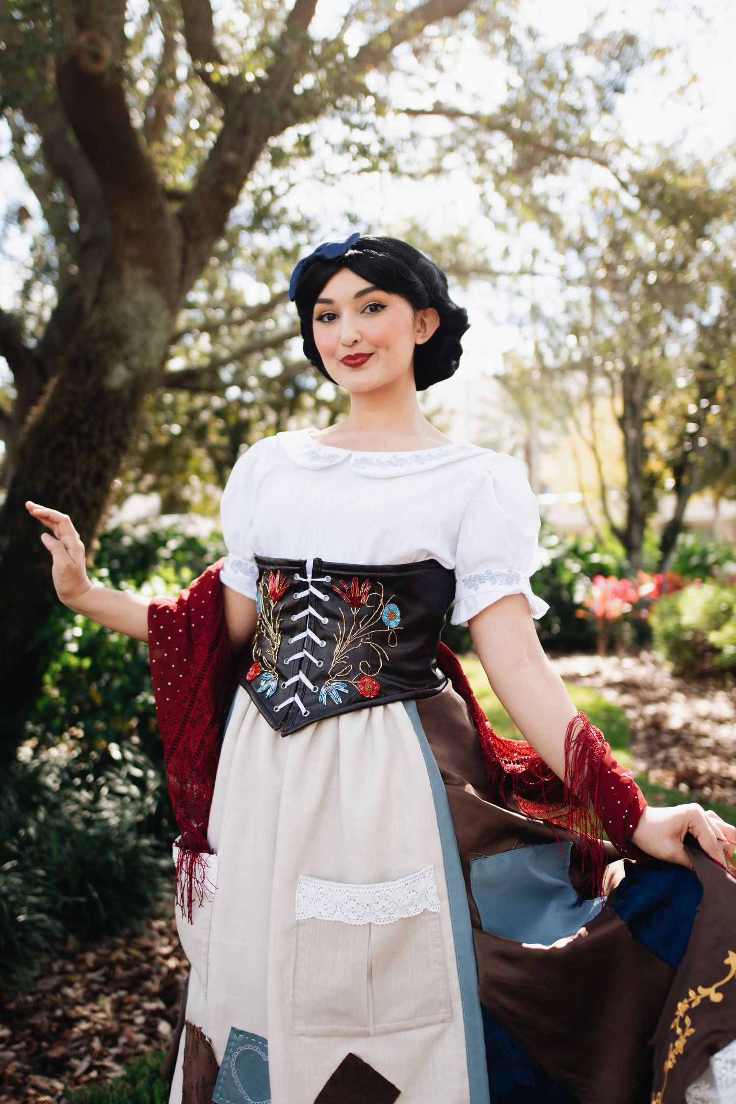 A folk costume with embroidered corset and patchwork dress in a garden setting.