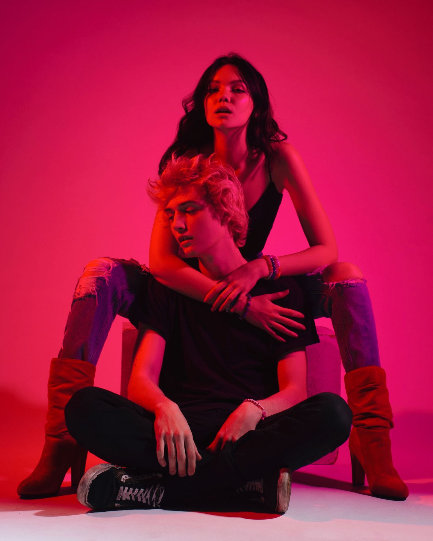 Fashion series with model in boots and dark clothing under intense red lighting.