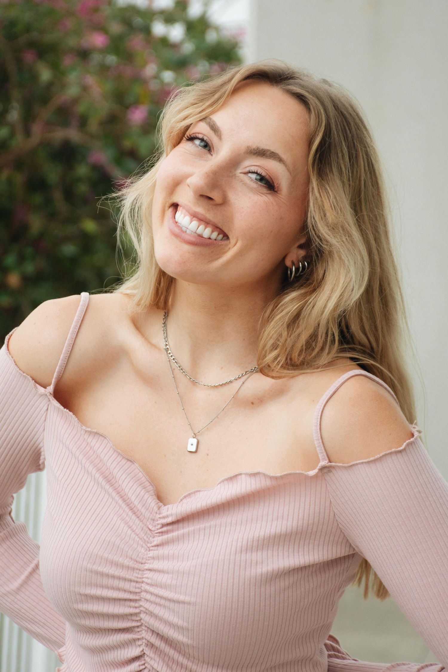 Candid portrait in pink off-shoulder top with joyful expressions.