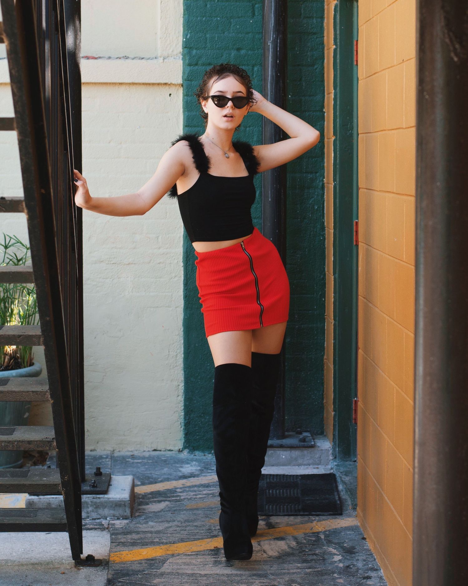 Urban fashion series with black and red outfit combinations against painted building exterior.