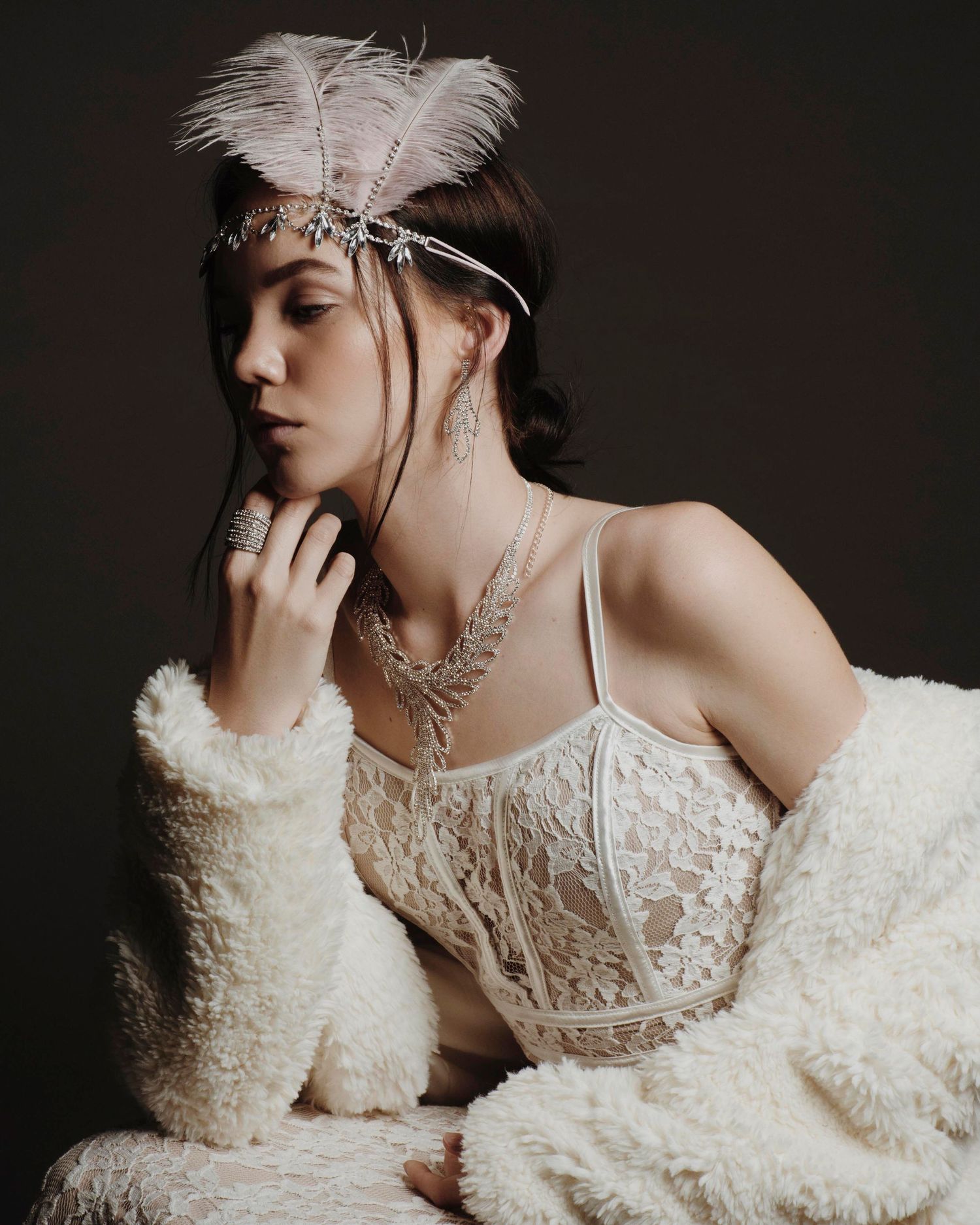 Ethereal portraits featuring white lace dress and feather accessories against dark background.