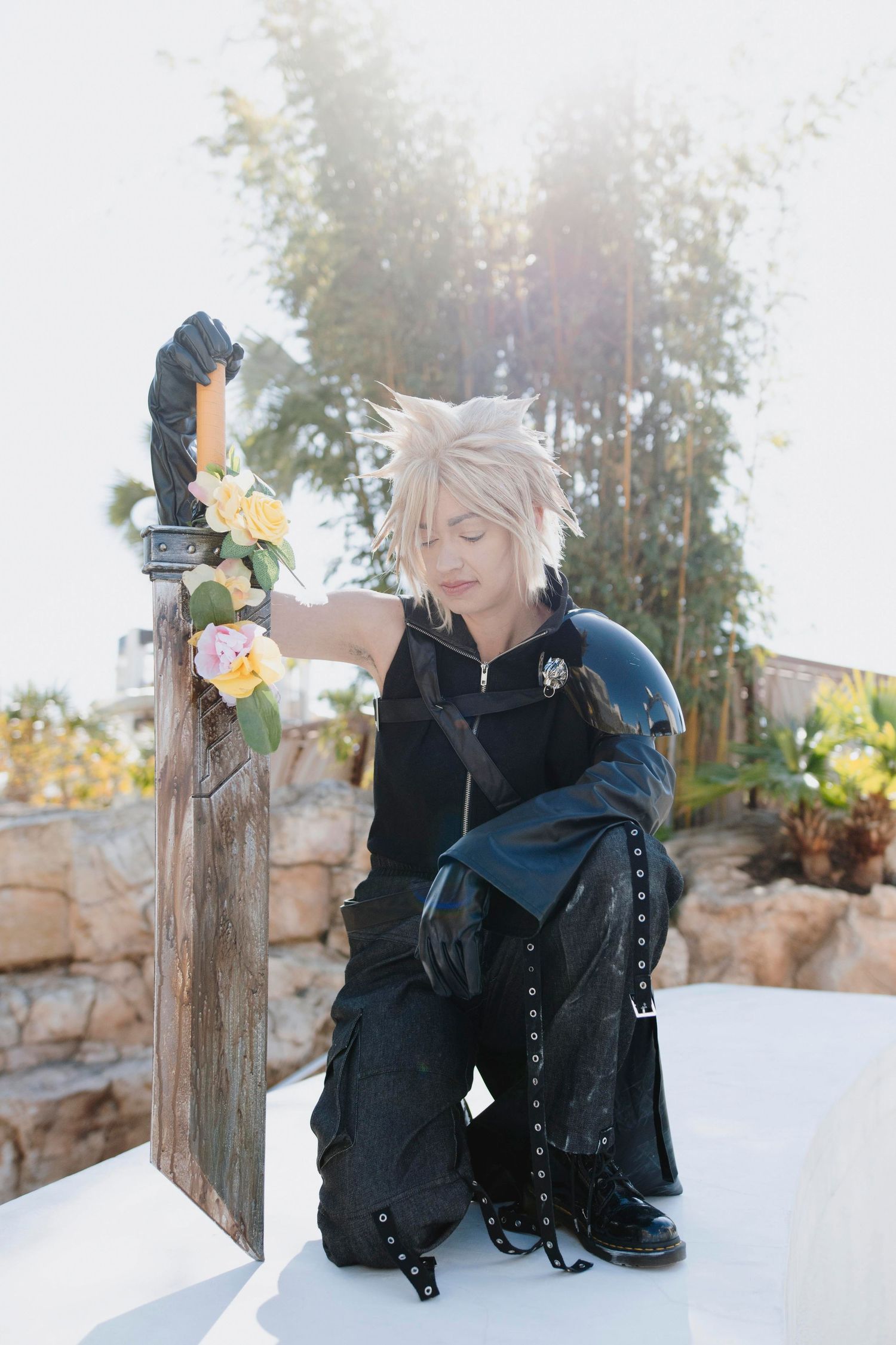 A cosplayer in a black outfit and white wig poses thoughtfully in a snowy winter scene with yellow flowers.
