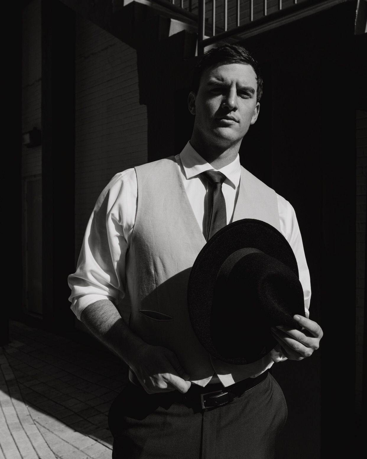 High contrast black and white portrait showing person in white shirt and dark vest.