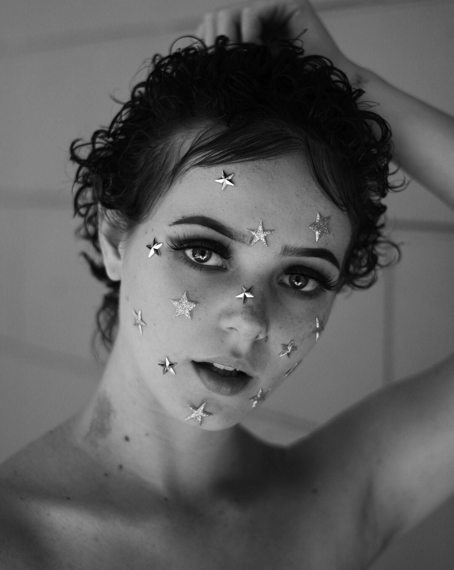 Black and white portrait with decorative star elements overlaid on face.