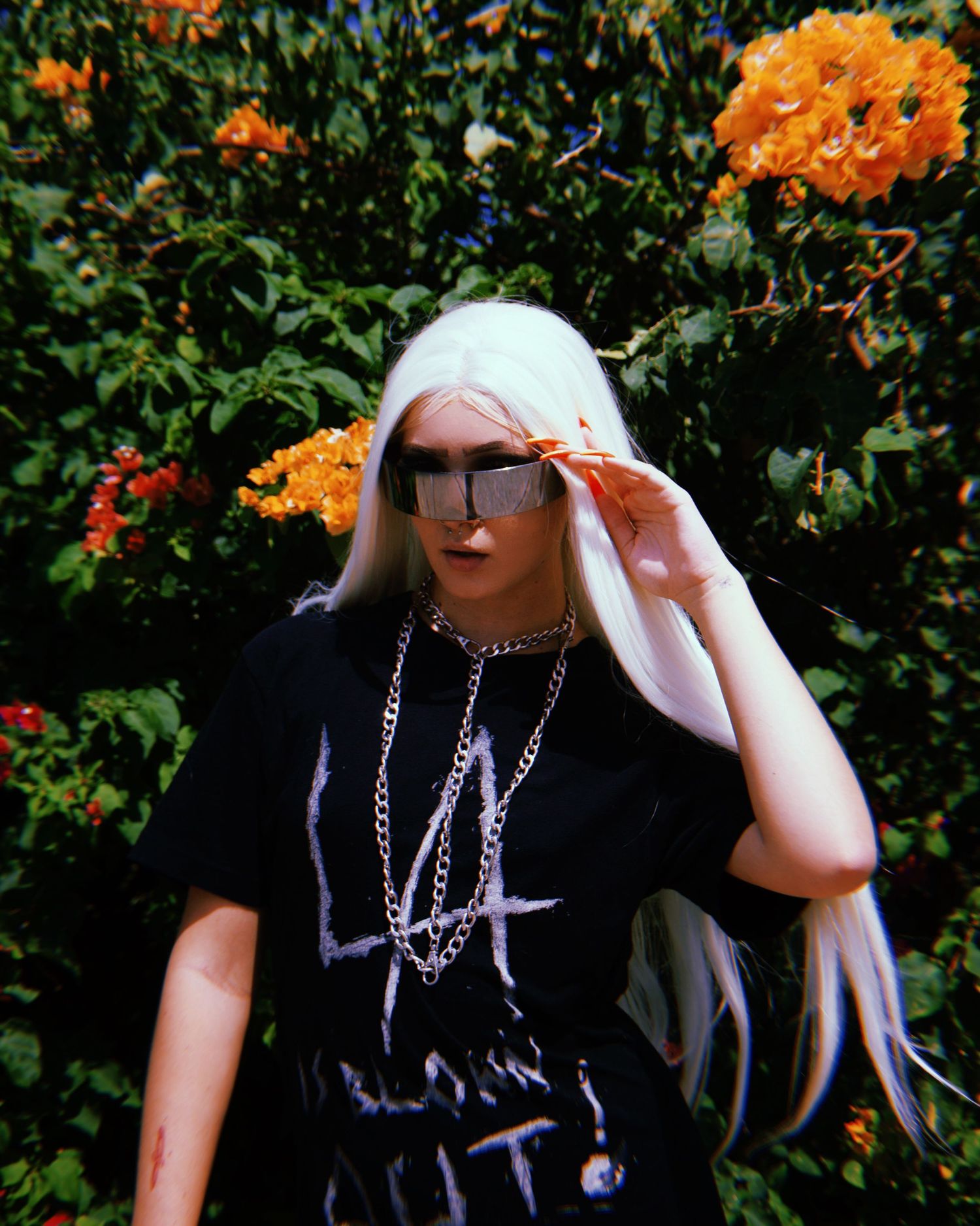 Artistic outdoor portrait series with black outfit and silver jewelry against orange flowers.