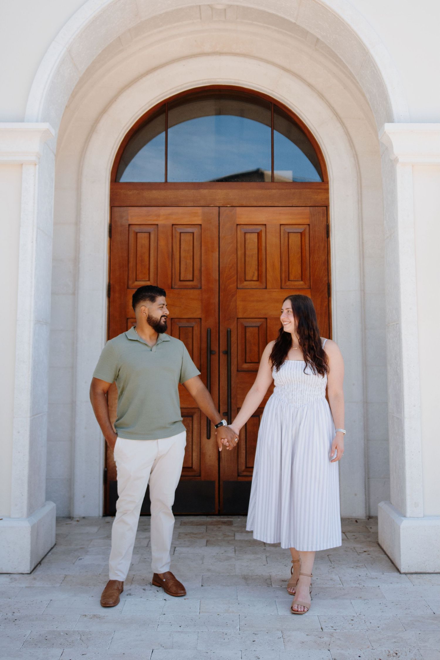 A couple poses in front of white arched doorways in a romantic photoshoot sequence.