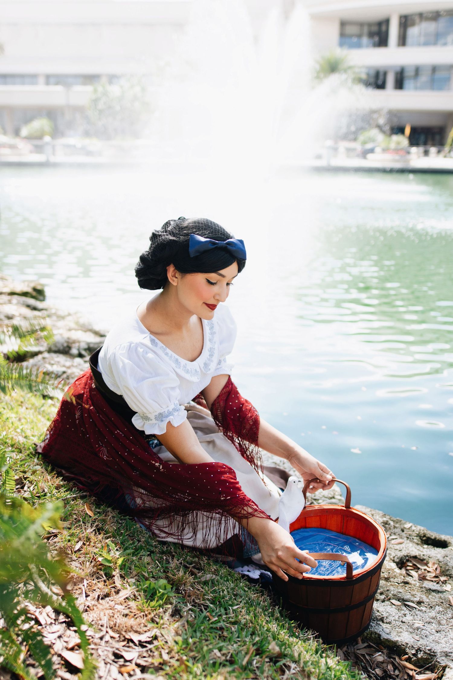 A vintage-inspired scene of washing clothes by a pond in fantasy costume.