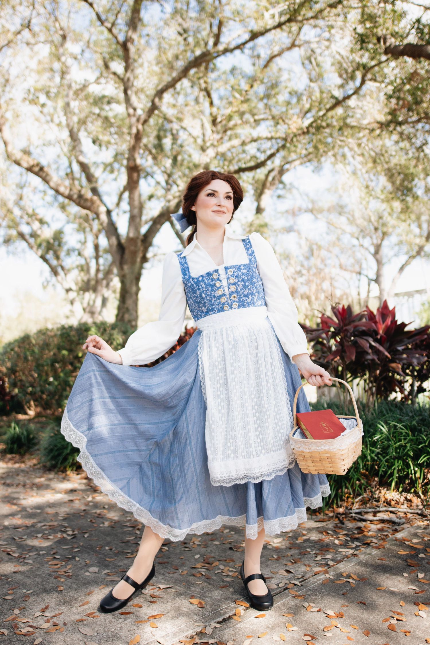 Vintage costume photoshoot featuring blue dress and white apron with wicker basket prop.