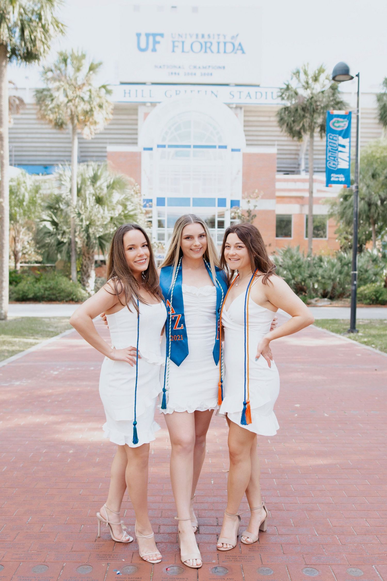 Graduation photoshoot at University of Florida campus with friends in white dresses.