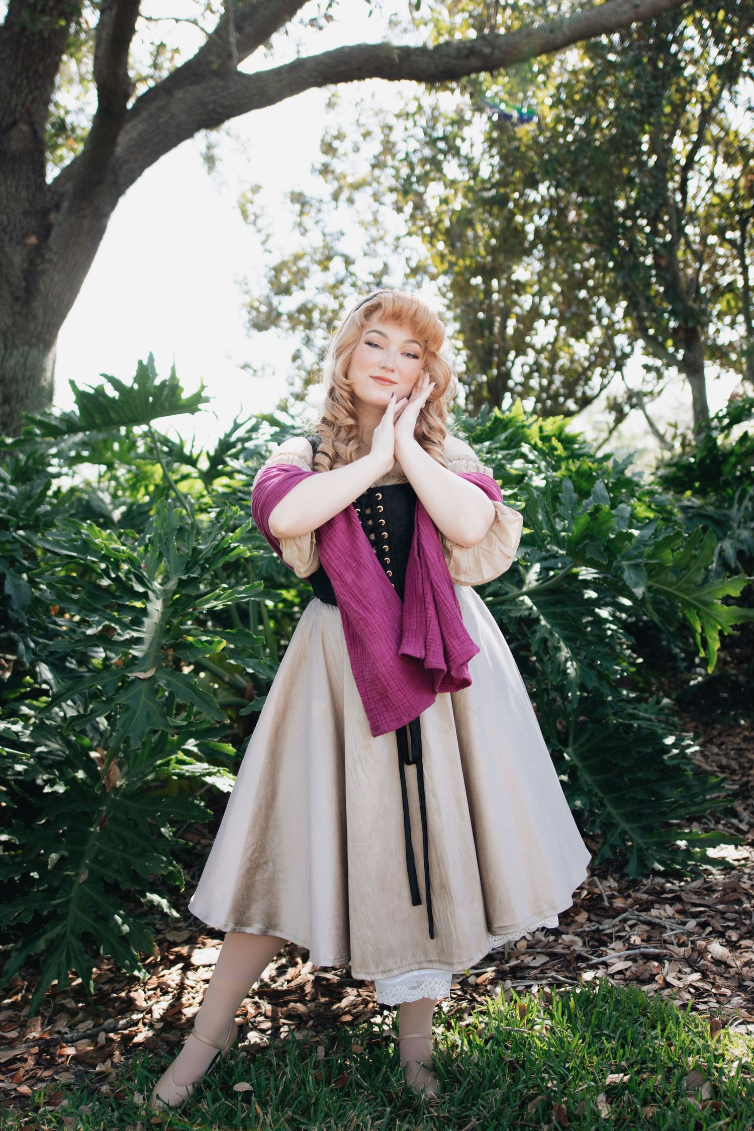 Theatrical poses in vintage beige dress and burgundy scarf on garden grounds.