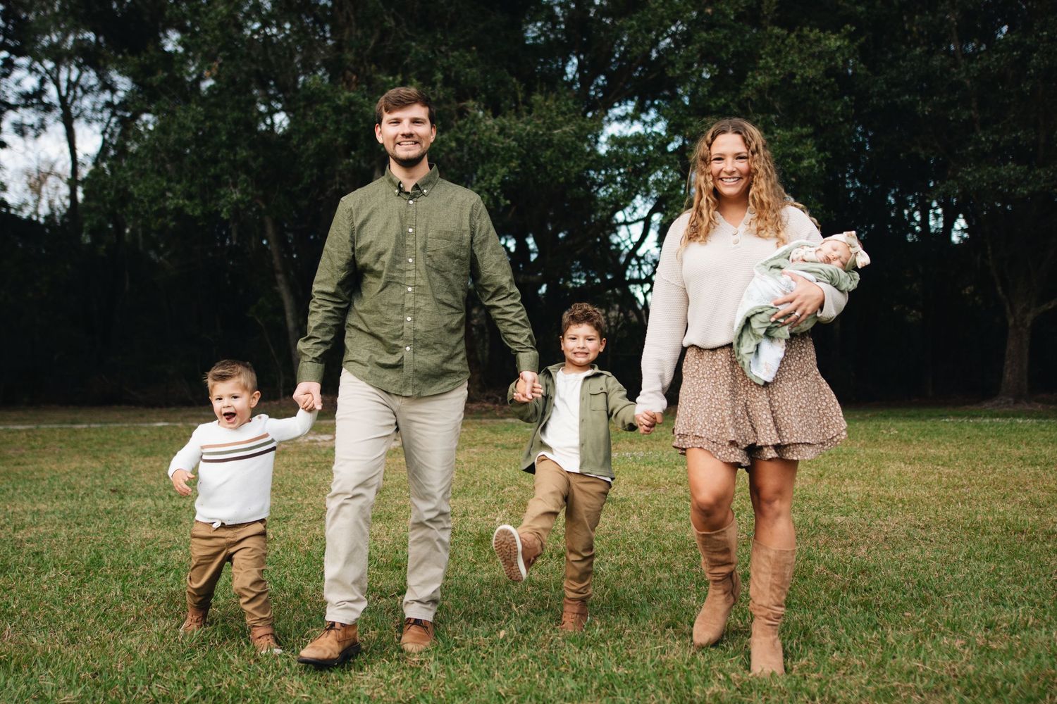 A group of people walking together on a grassy field in casual attire during a sunny day.