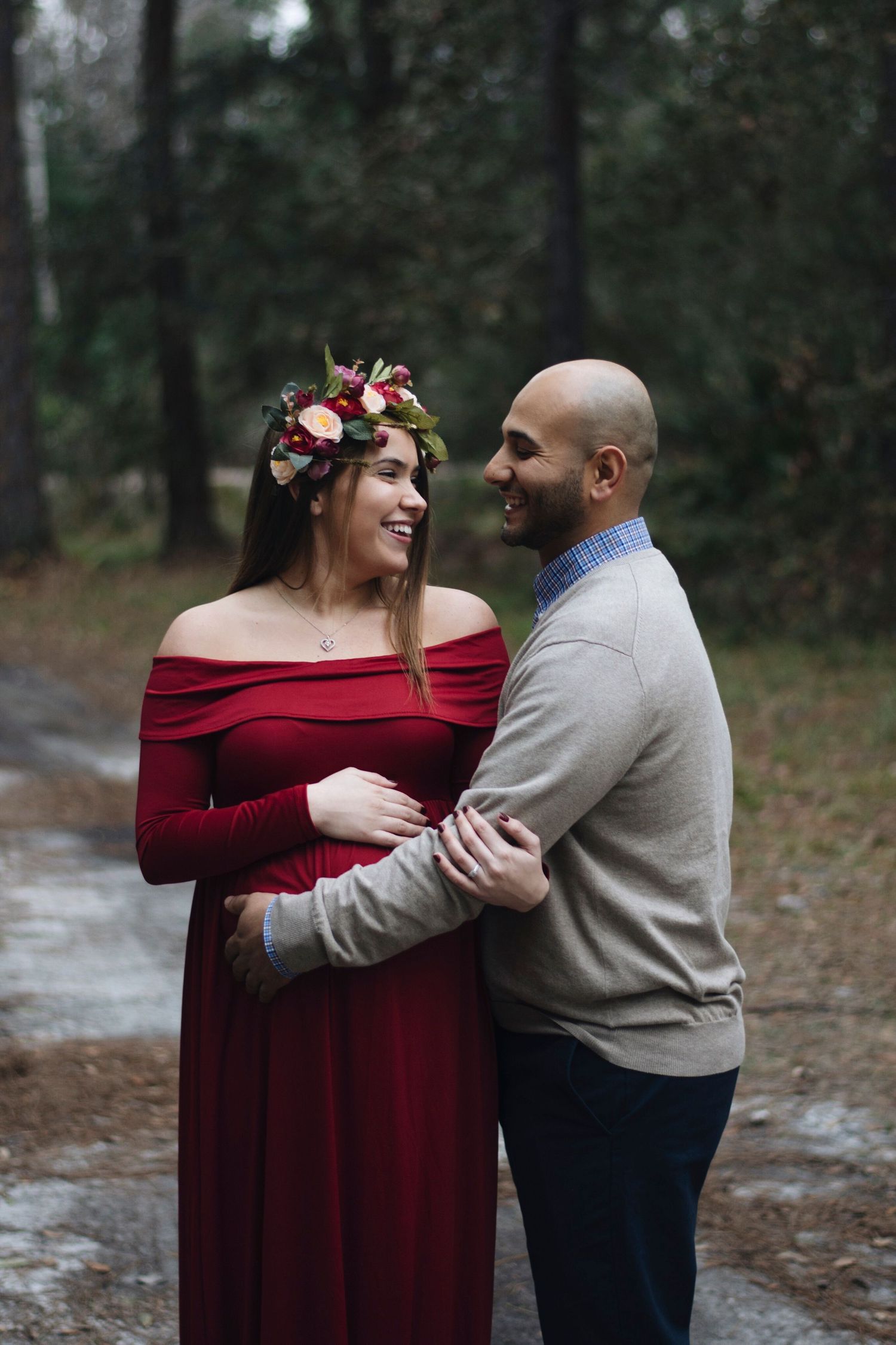 A couple shares intimate moments during their maternity shoot in a forest setting.